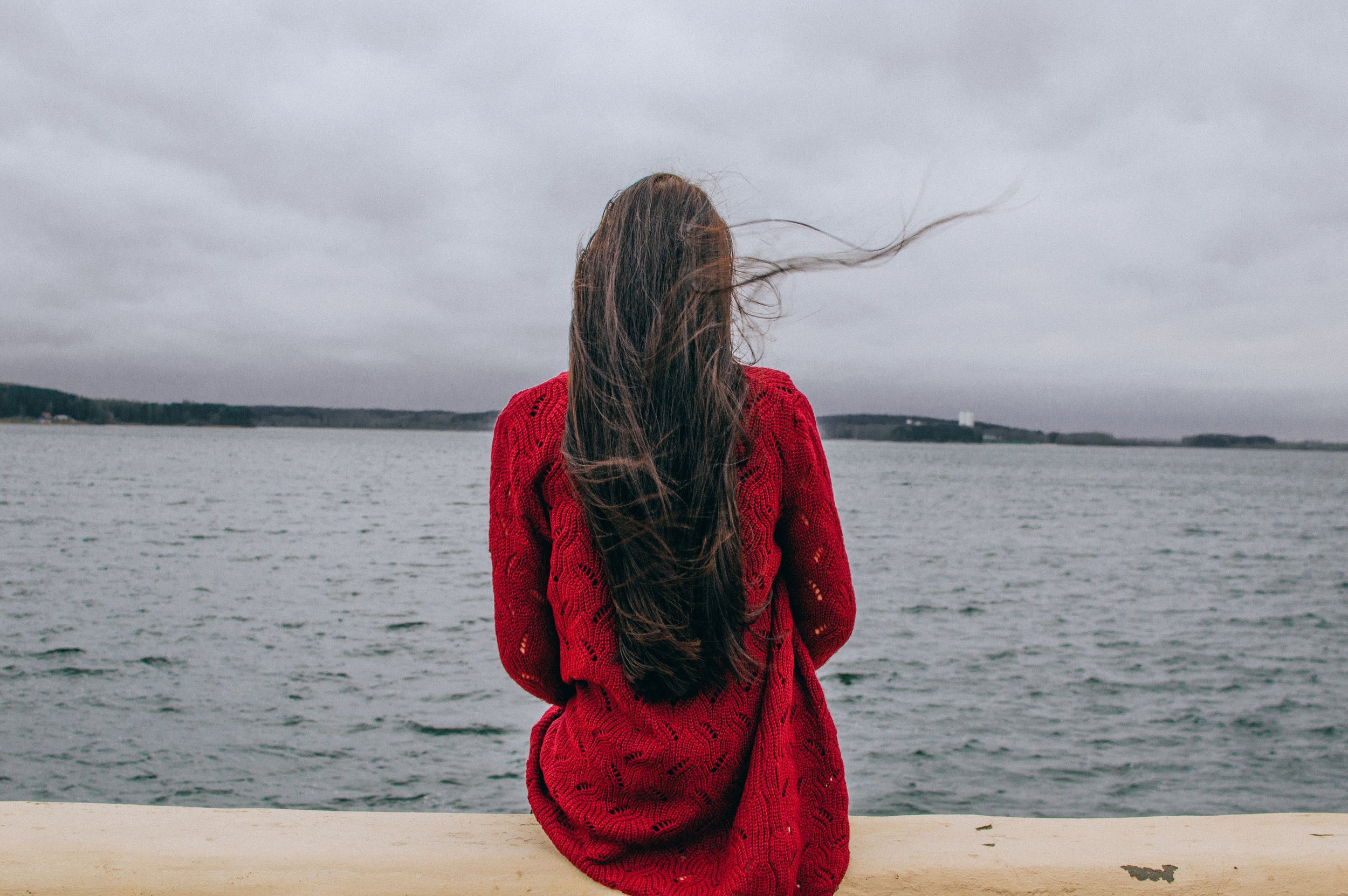 Person sitting alone by a lake reflecting on emotional longing, attachment patterns, and the role fandom can play in connection, fantasy, and belonging.