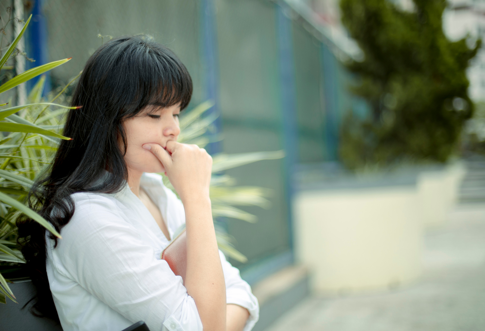 A woman standing alone outdoors in quiet reflection, illustrating the nervous system strain of being low maintenance and emotionally self-contained.