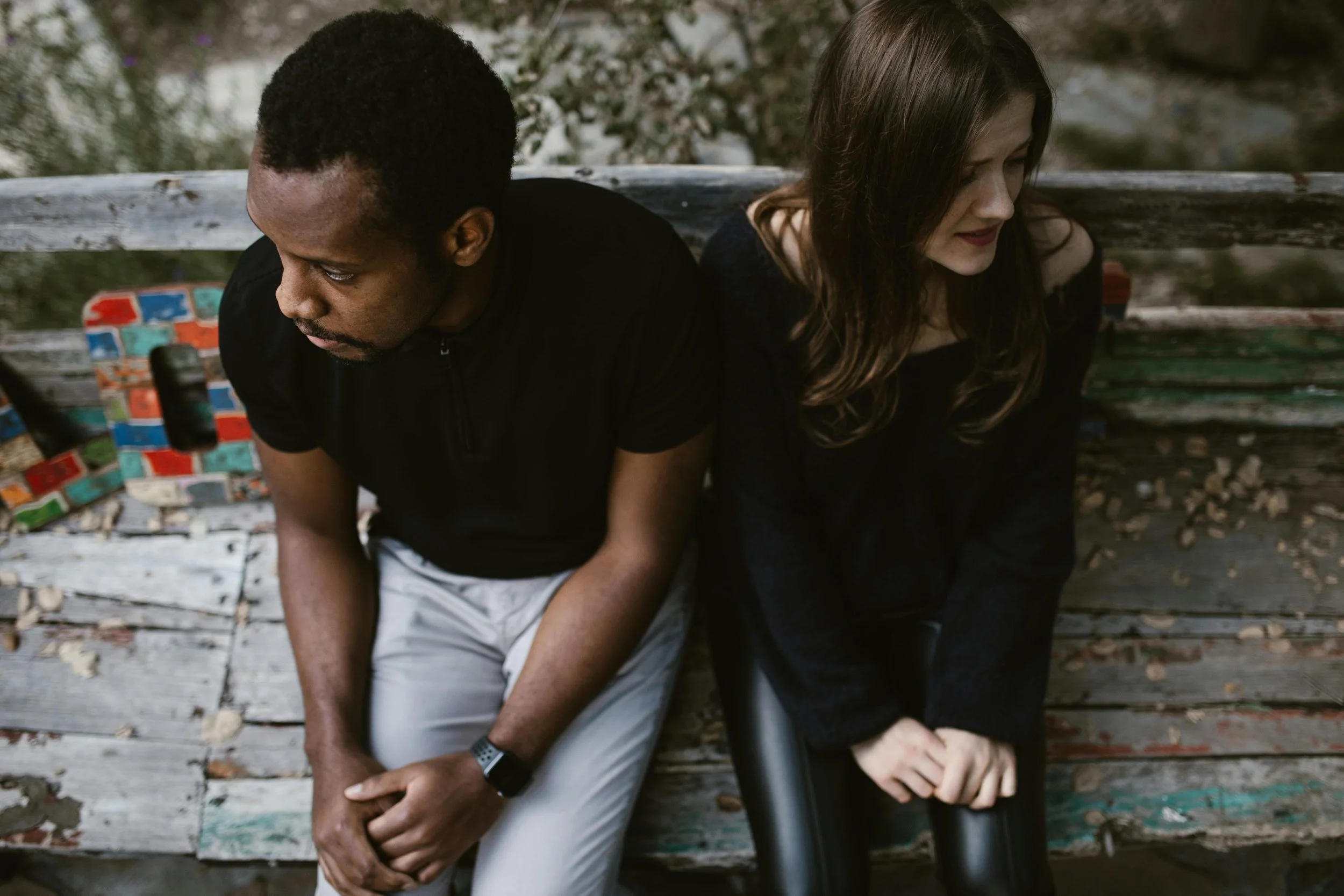Couple sitting apart on a bench looking away from each other, capturing emotional distance and grief after a breakup caused by incompatibility and future misalignment.
