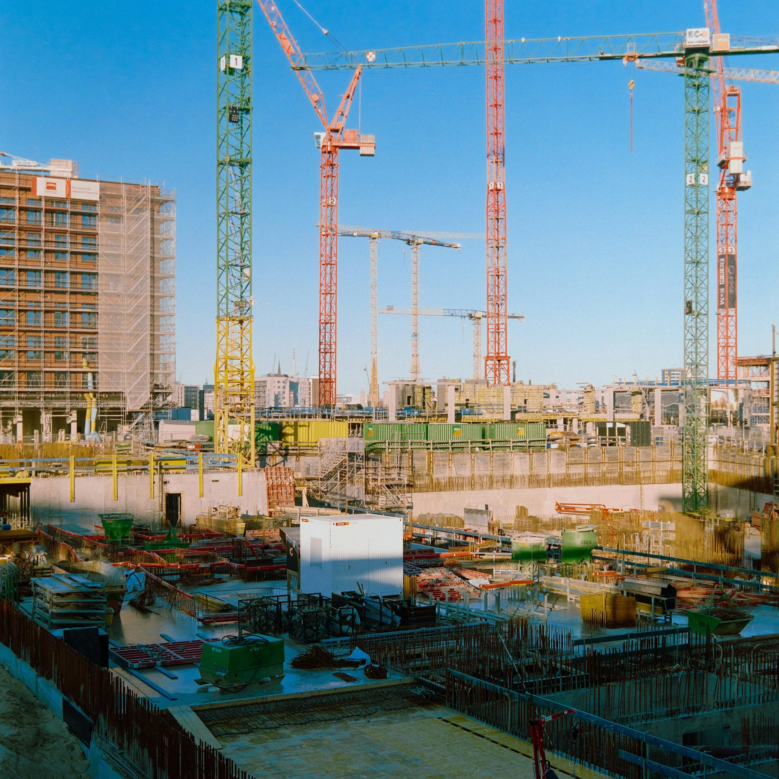 Construction site with cranes and building framework against a clear blue sky.