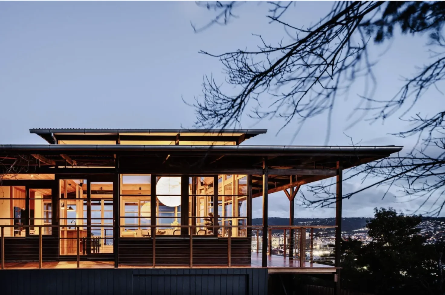 Japanese-inspired architectural extension with timber wrap-around deck overlooking Hobart city lights at dusk, Seaview Glebe Tasmania