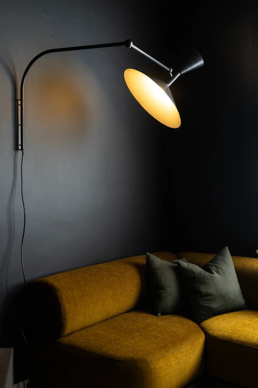 Mustard velvet sofa with dark green linen cushions and arc wall lamp against deep charcoal walls, Ogee Guesthouse North Hobart Tasmania