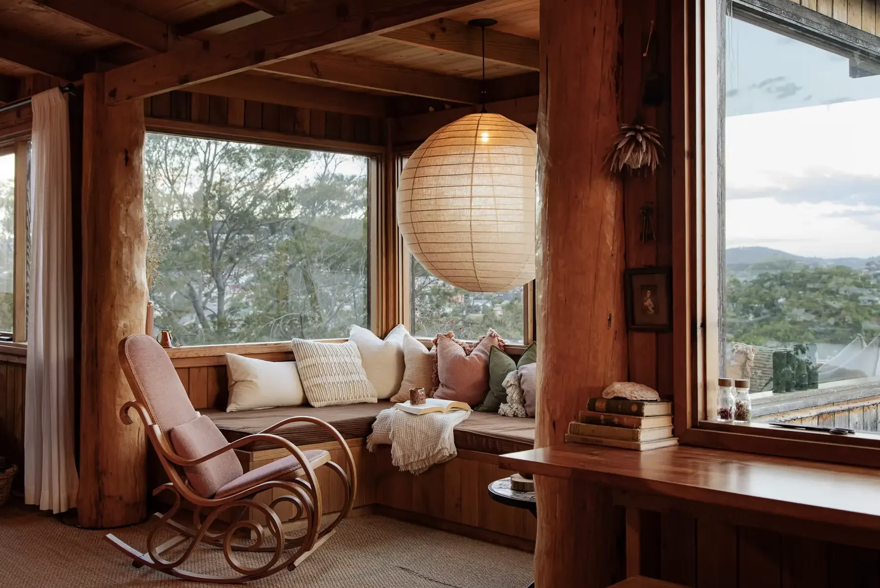 Timber window seat with cushions and rocking chair overlooking Derwent River and Hobart hills, Del Sol Treehouse Rosny Tasmania