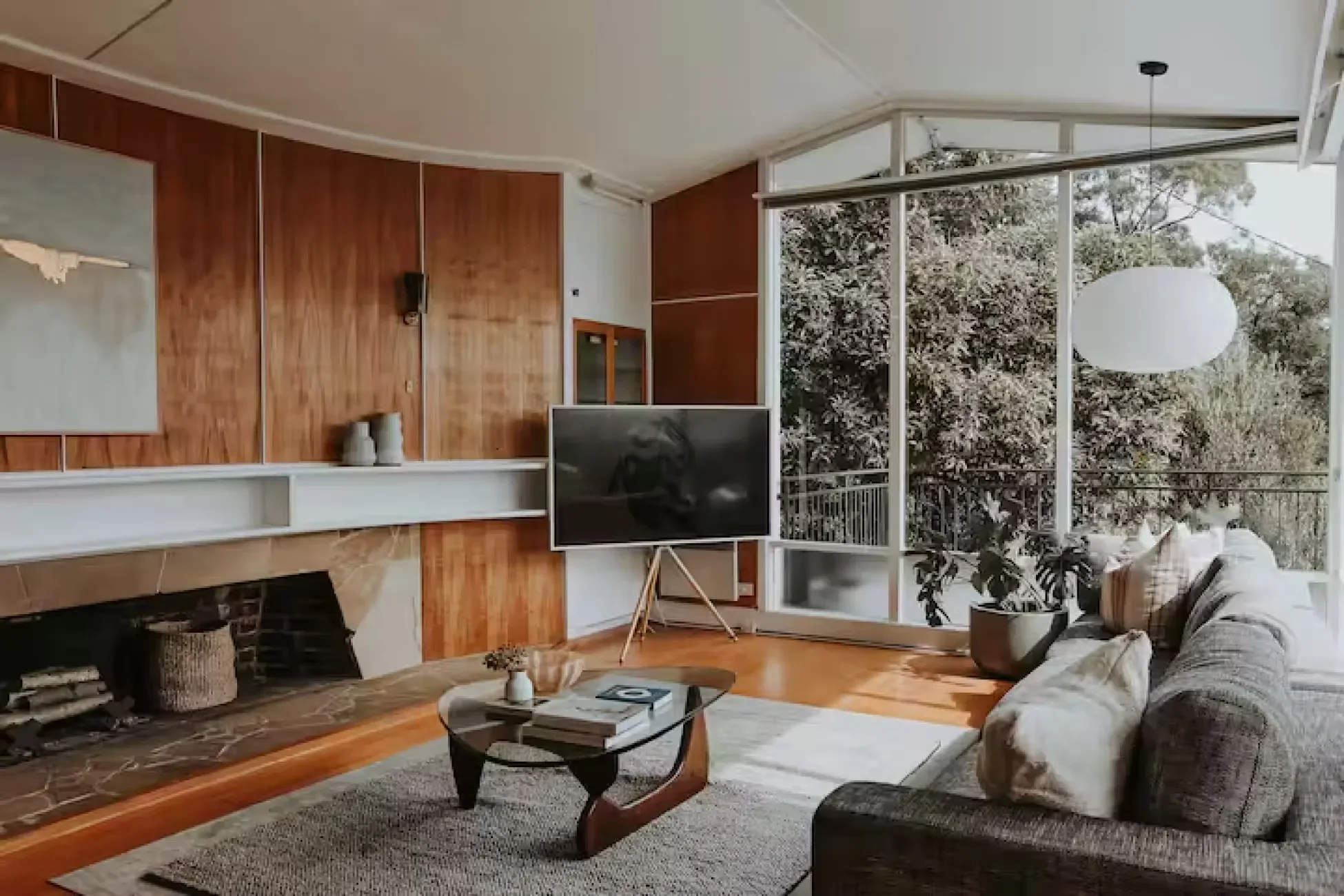 Mid-century modern living room with curved ceiling, original timber wall panelling, stone fireplace and floor-to-ceiling glass, Esmond house Sandy Bay Hobart Tasmania