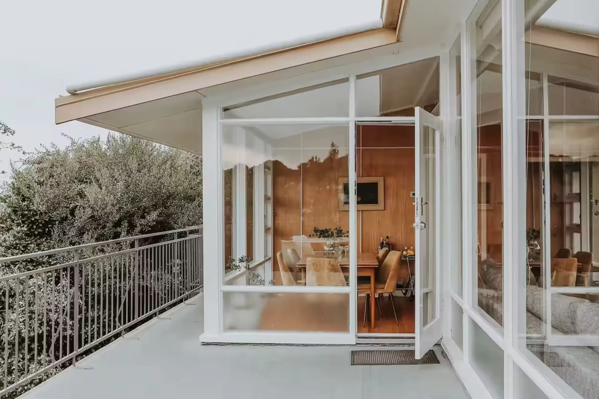 Mid-century modern dining room with original timber wall panelling and period olive velvet chairs viewed through glass door, Esmond house Sandy Bay Hobart Tasmania