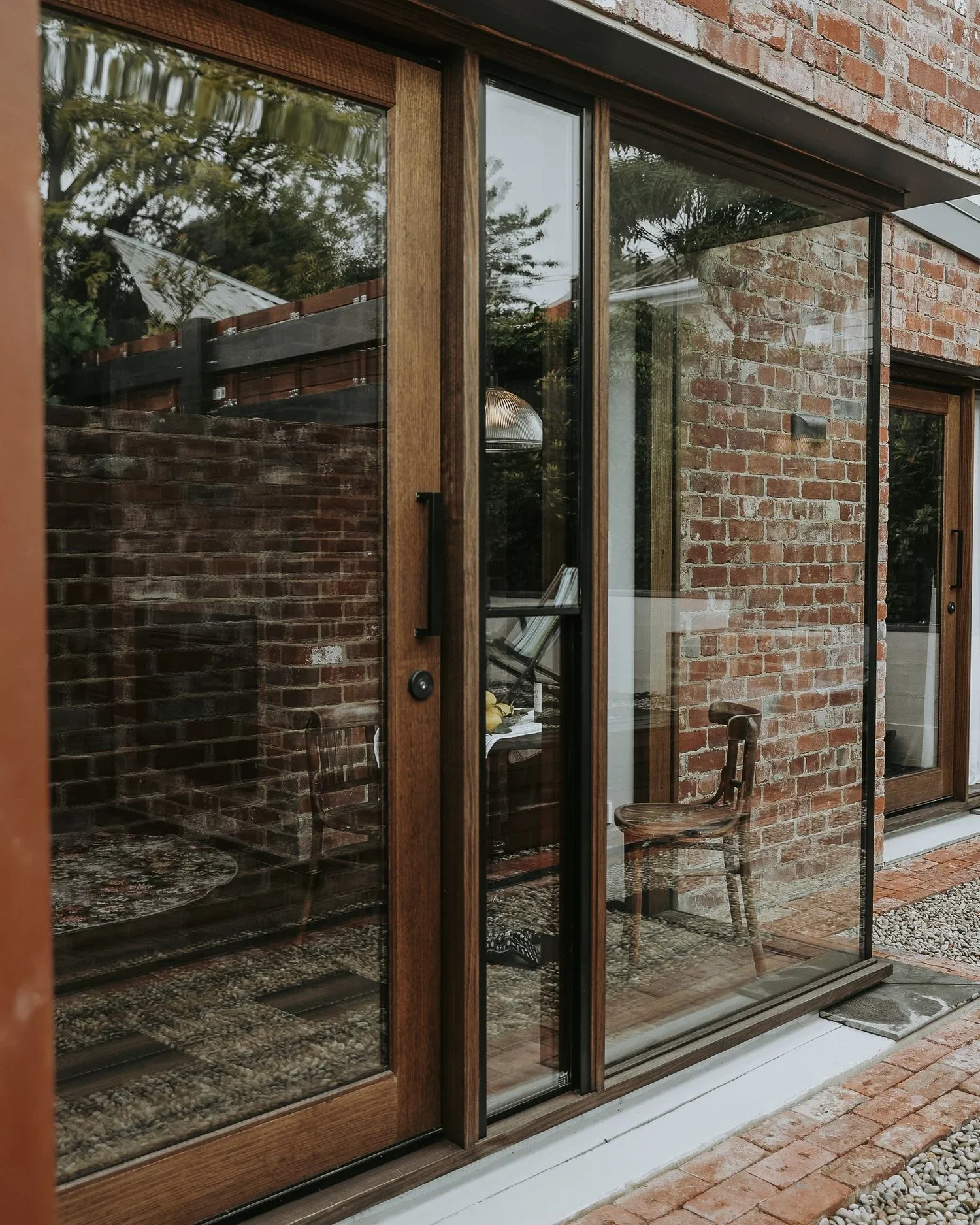 Heritage red brick exterior with timber-framed floor-to-ceiling glass doors and pebble courtyard, Braithwaite Hobart, Sandy Bay Tasmania