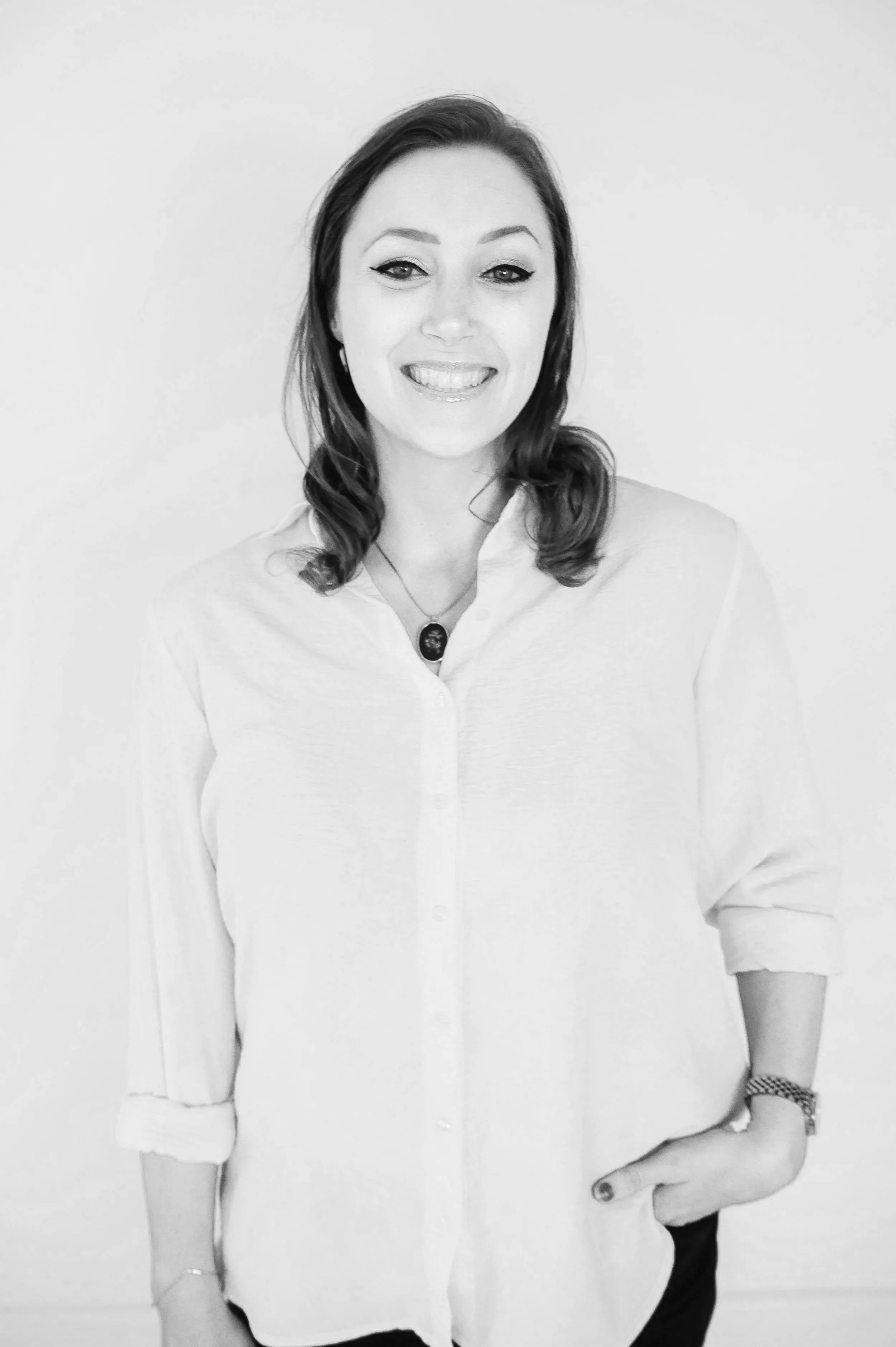 Black and white portrait of a woman with long, wavy hair, wearing hoop earrings, a striped shirt, and smiling.