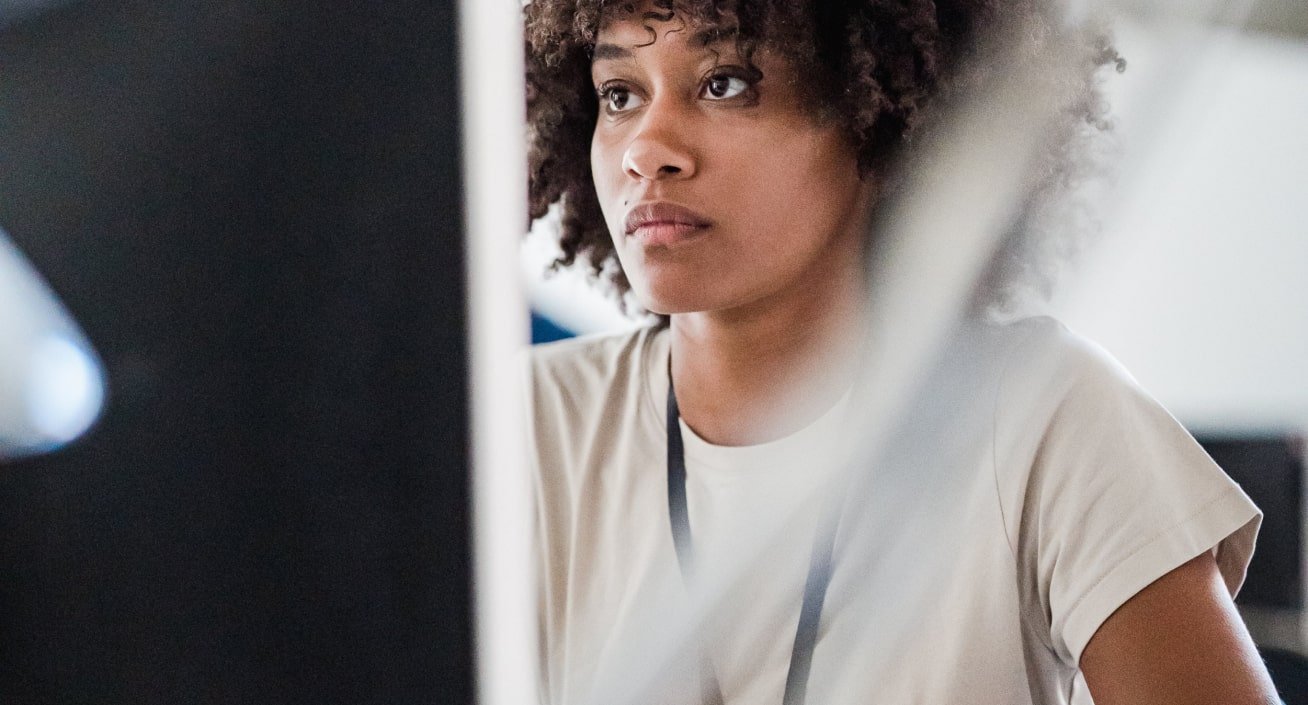 A woman with curly hair working at a computer in an office setting.