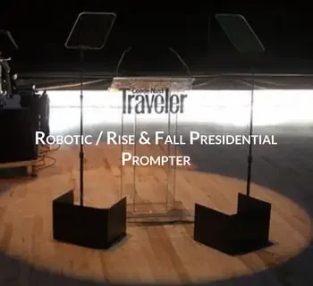 Stage setup with two microphone stands and two black chairs, background features a screen with the text 'Connect North Traveler Robotic / Rise & Fall Presidential Prompter'