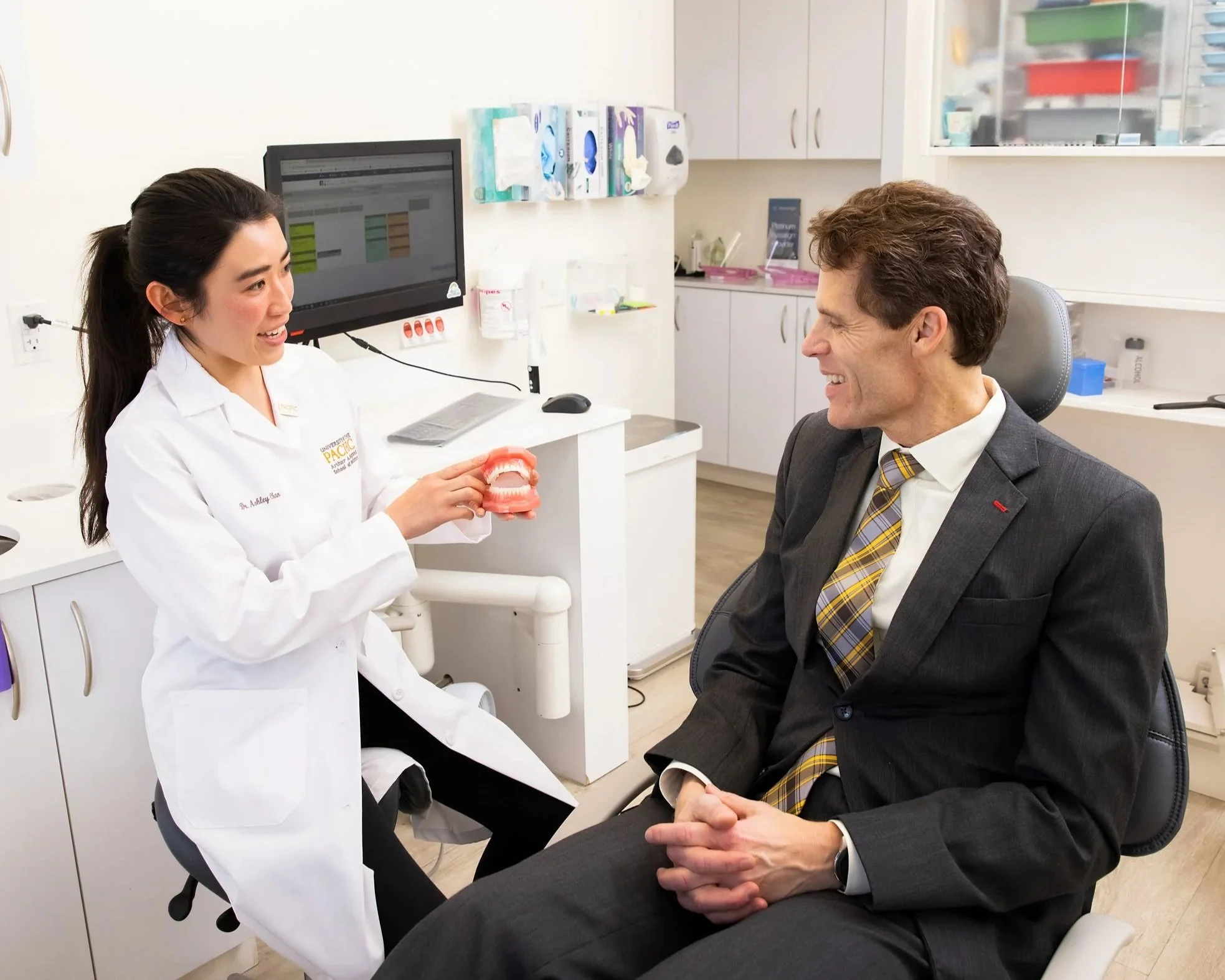 Dr. Ashley Chan explaining a treatment plan using a dental model during a patient consultation at Young Dental Group in San Mateo.
