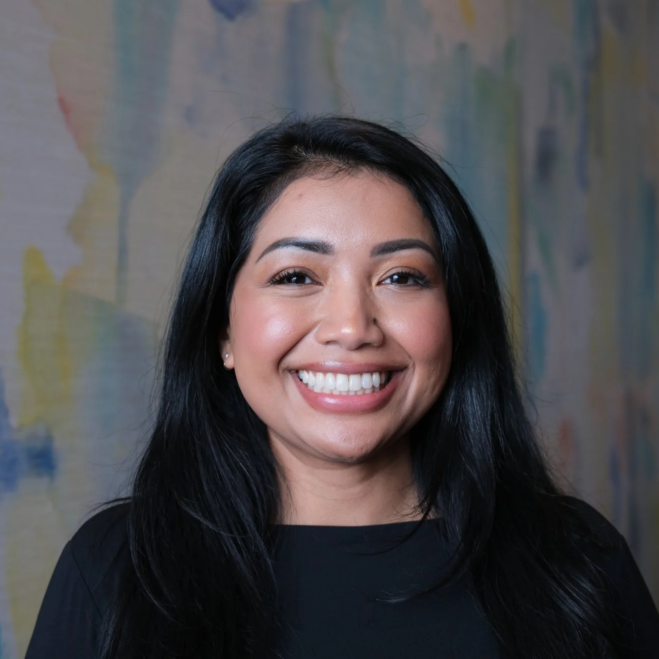 Erika Keo in front of a white, blue, yellow backdrop.