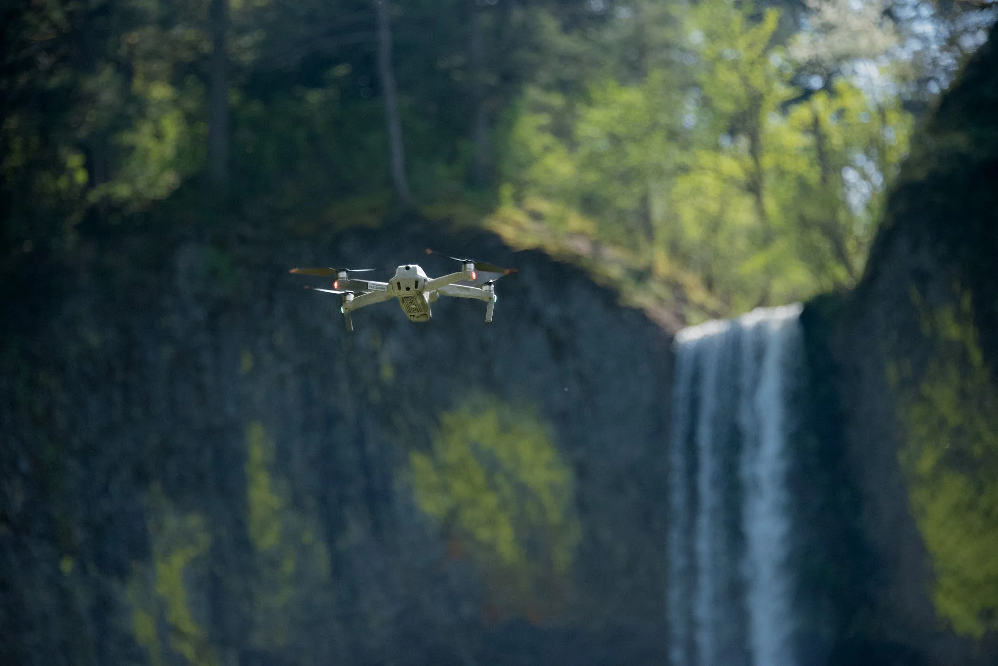 photograph of drone in flight with waterfall in background
