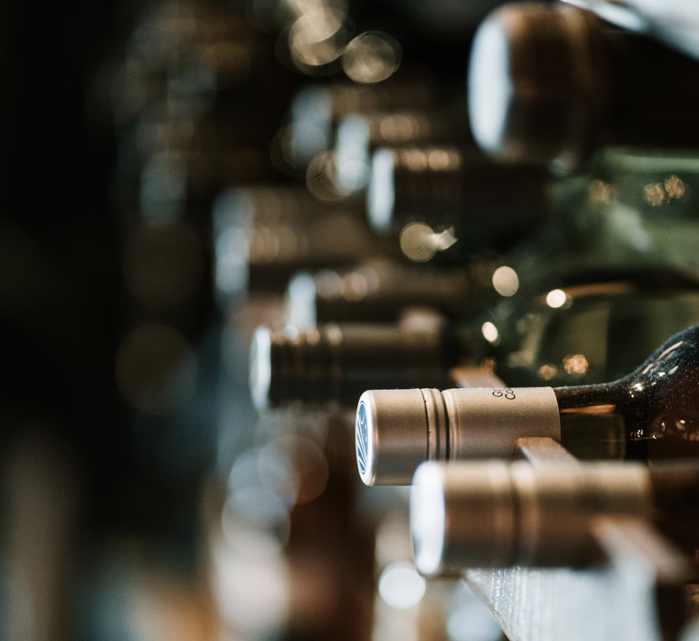 Wine bottles stored on a rack in a dimly lit wine cellar.