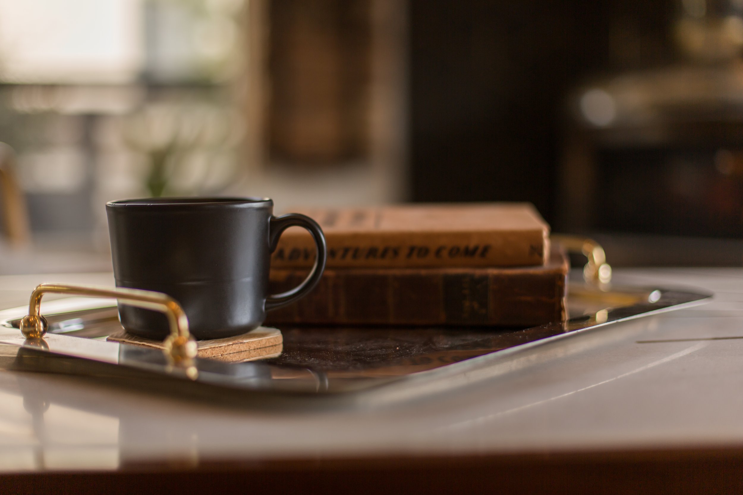 A black cup on a tray next to two stacked books on a kitchen countertop.