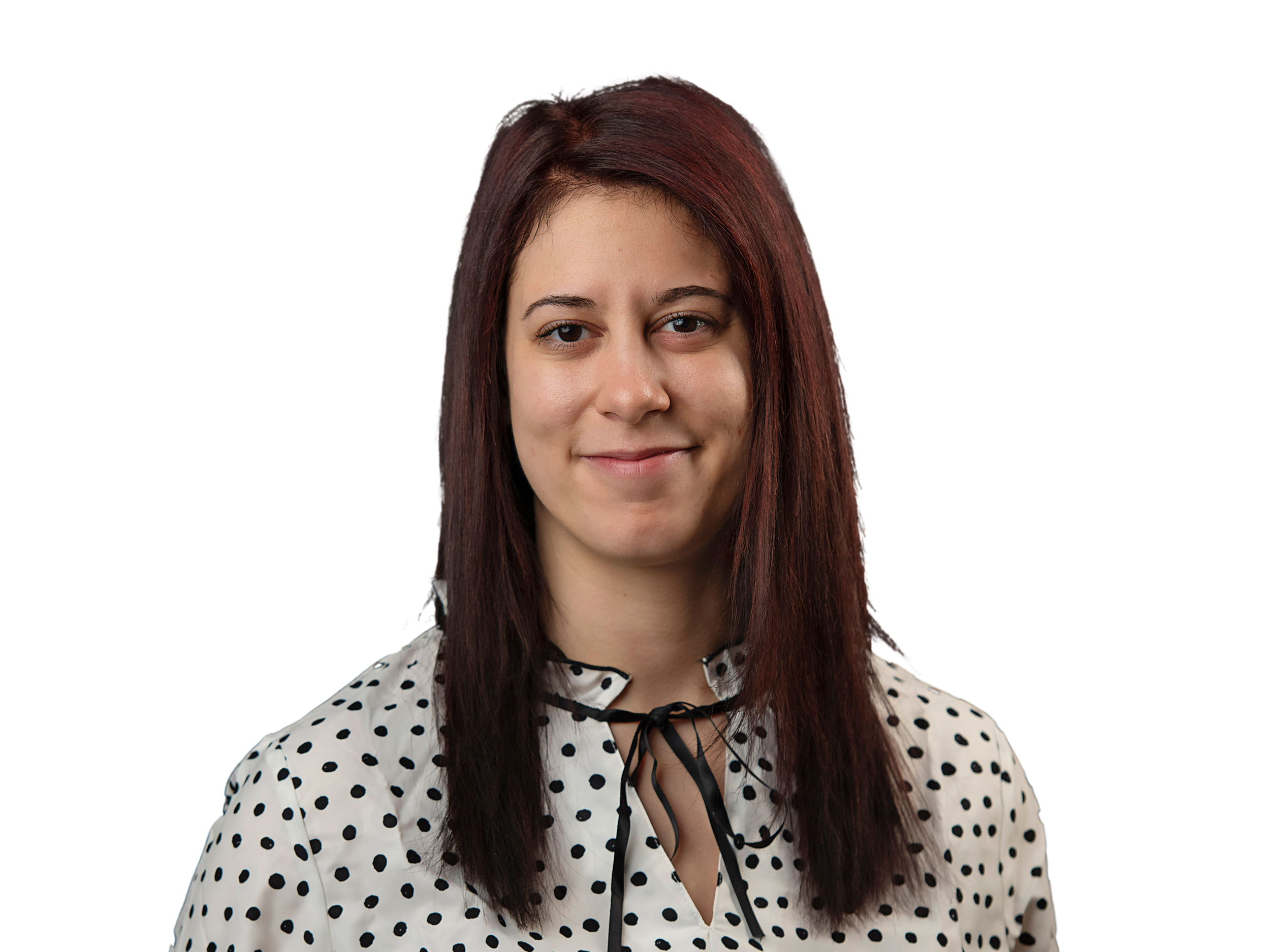 A woman with long dark red hair, wearing a white blouse with black polka dots and black lace-up details, smiling at the camera against a digital blue and purple background.