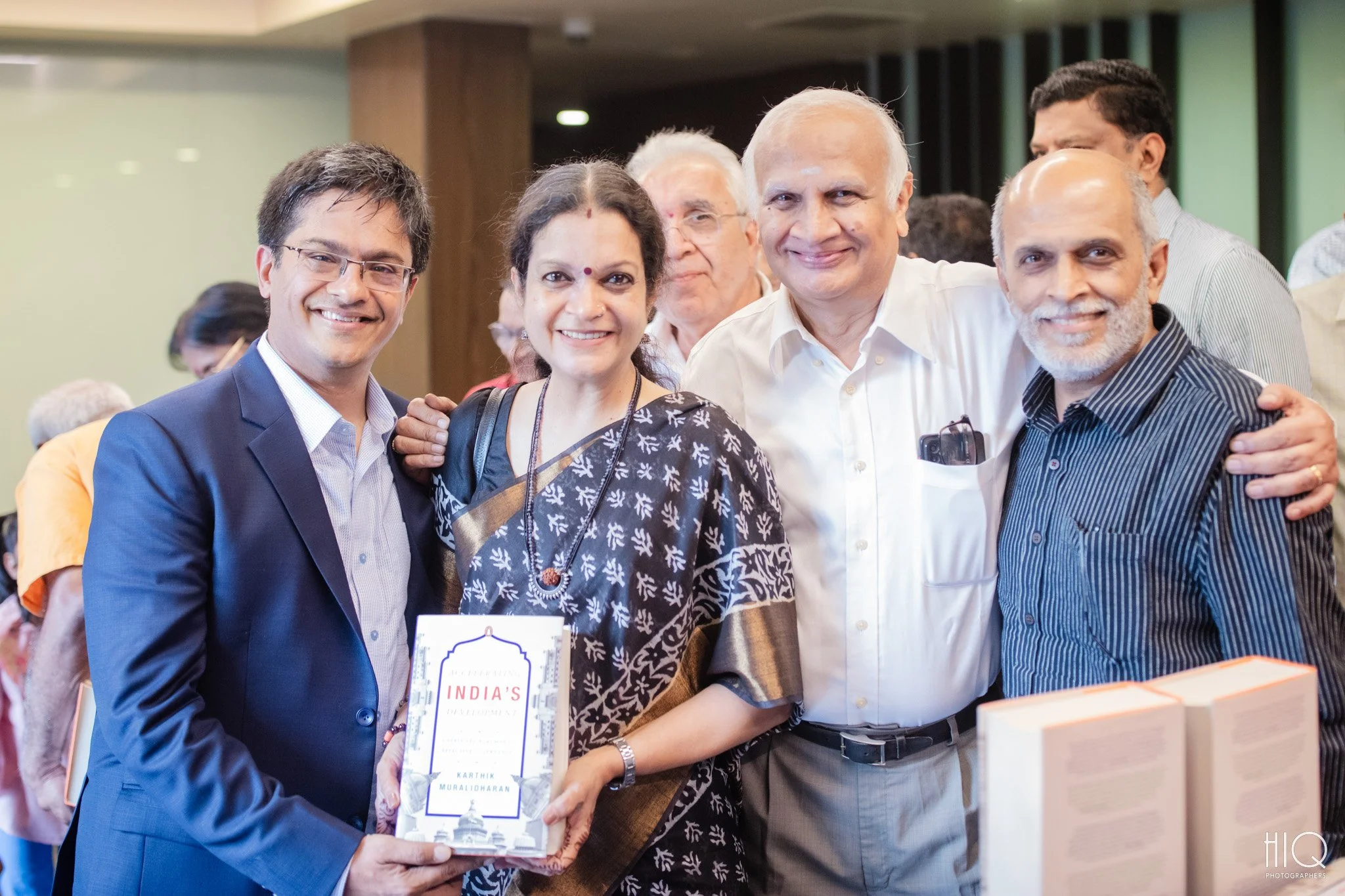 Group of five people smiling at a book event, with one woman holding a book titled 'India's Development'.