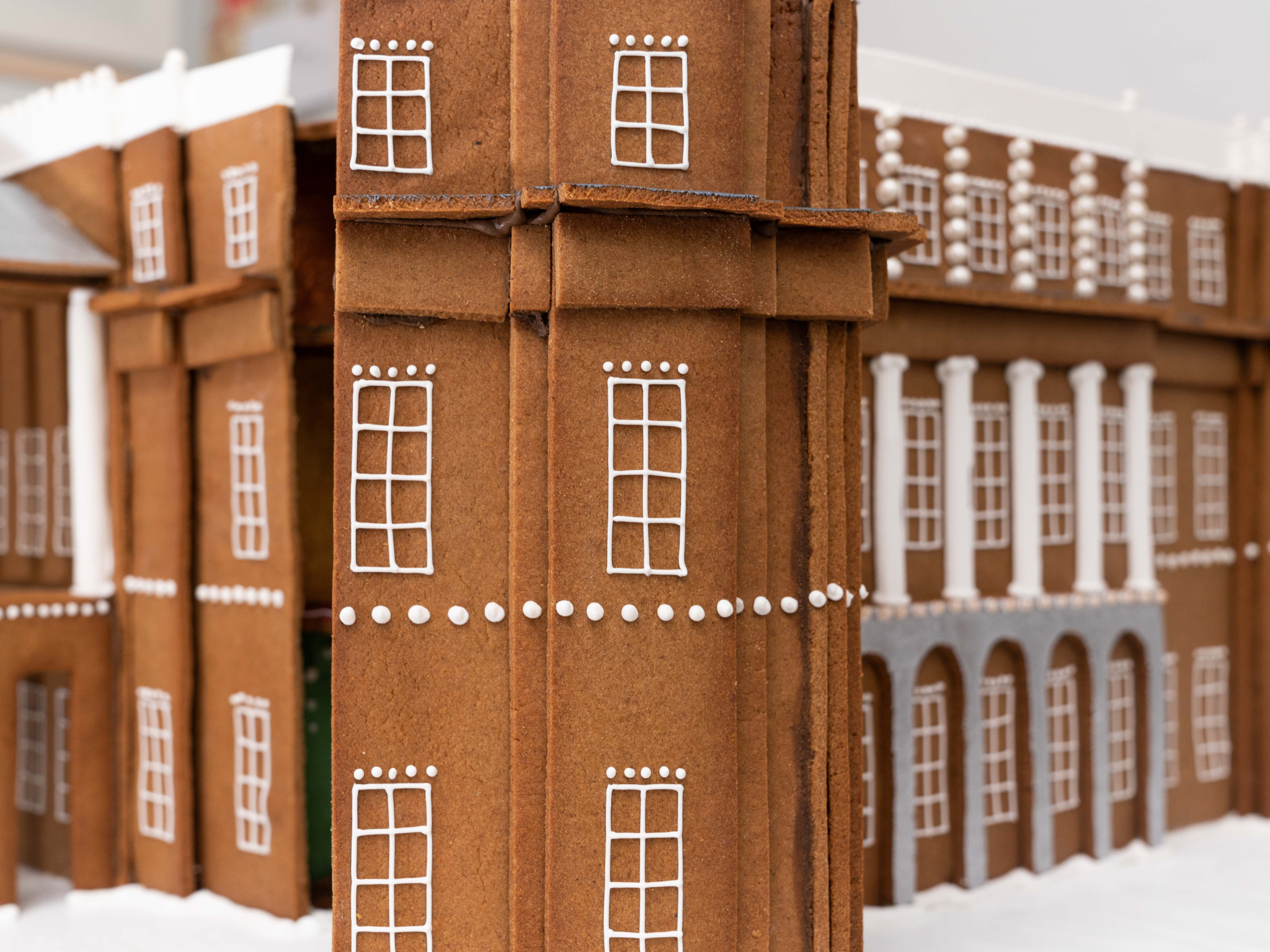 Gingerbread house with white icing window details and columns.