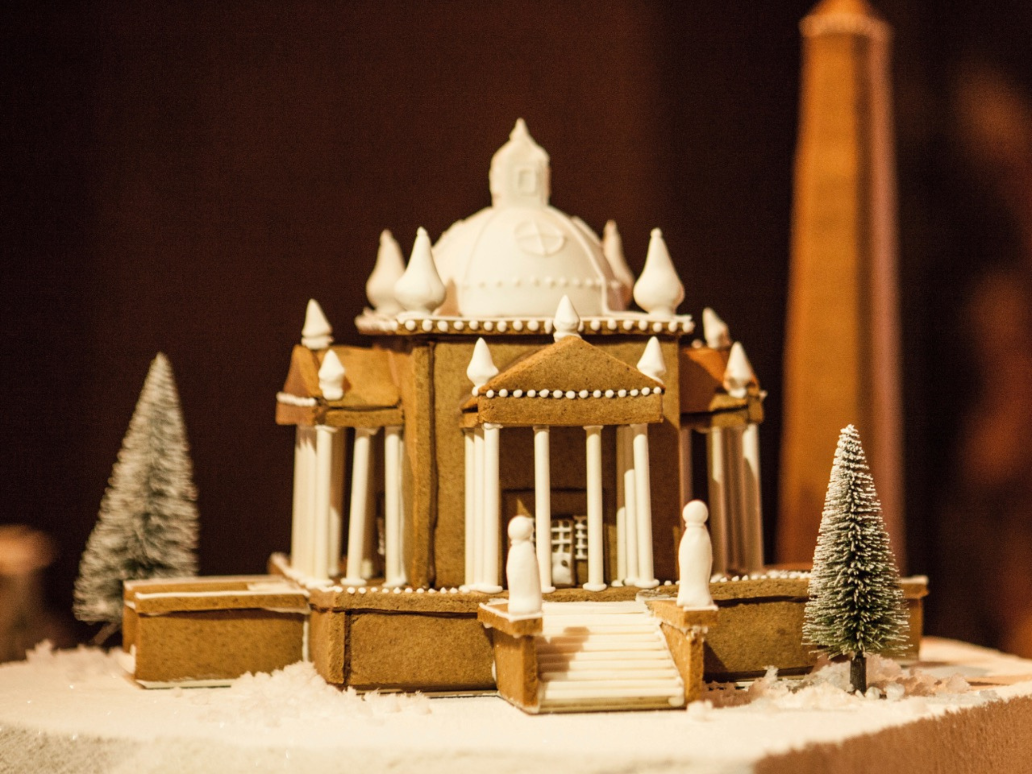 Temple of The Four Winds in gingerbread house form, decorated with white icing, with small white icing sculptures and Christmas trees.