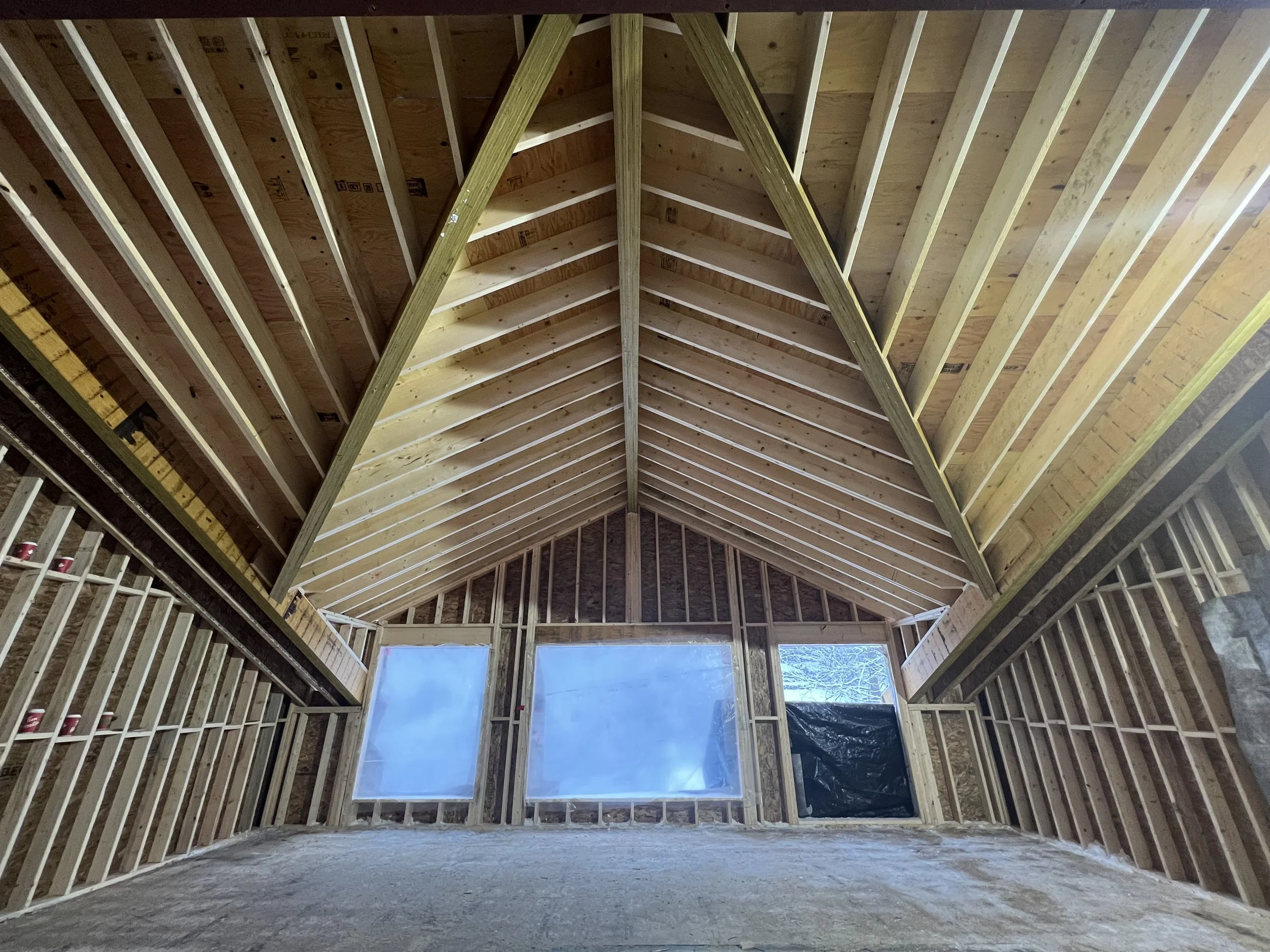 A-frame house construction, view of wooden interior framing with large windows.