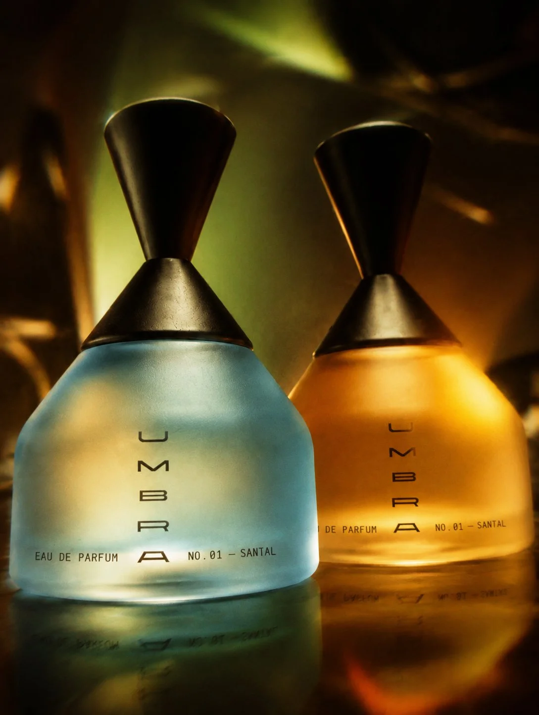 Blue and amber UMBRA eau de parfum bottles in cinematic light
