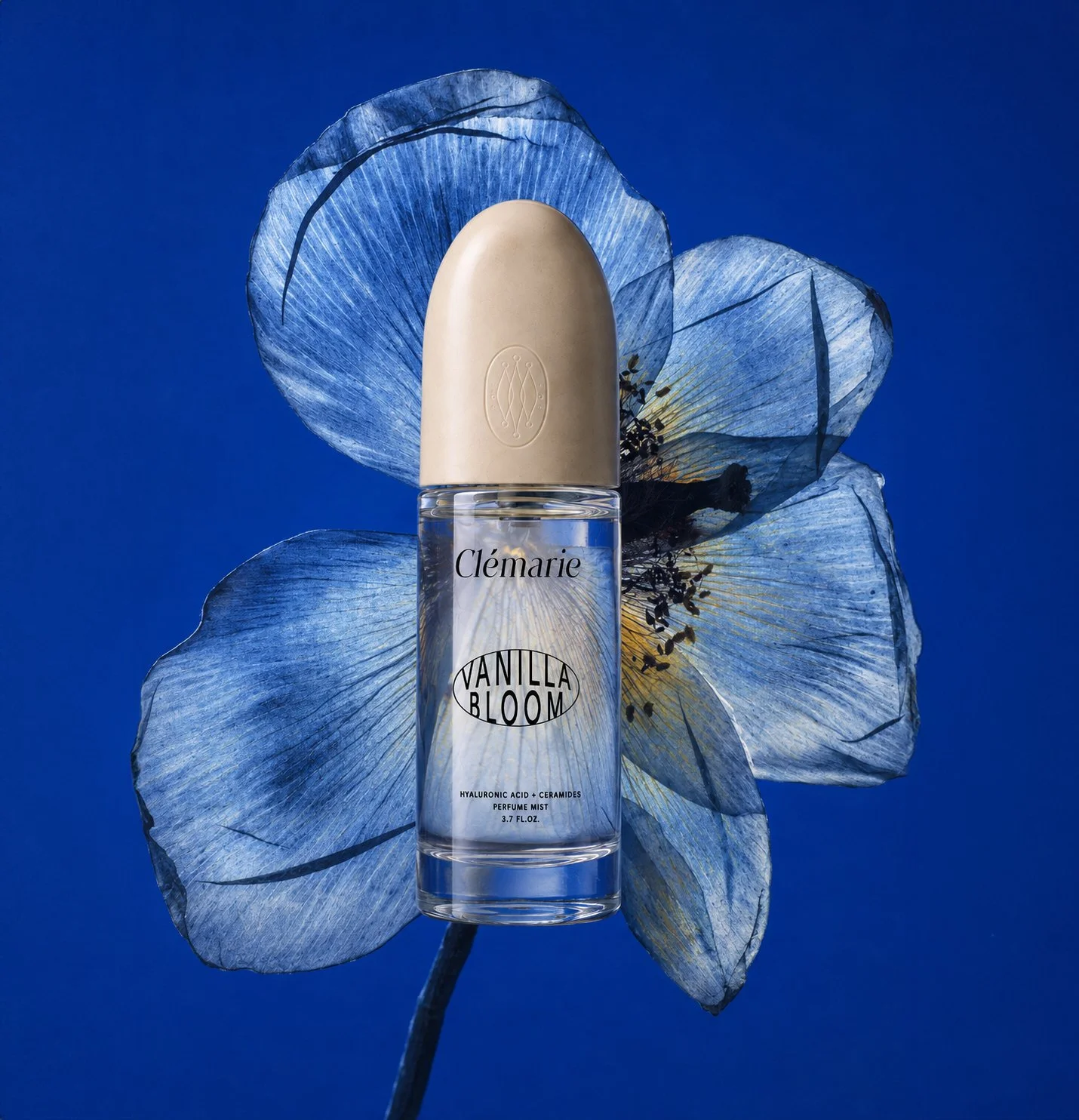 Transparent Clémarie skincare bottle presented against a large blue flower