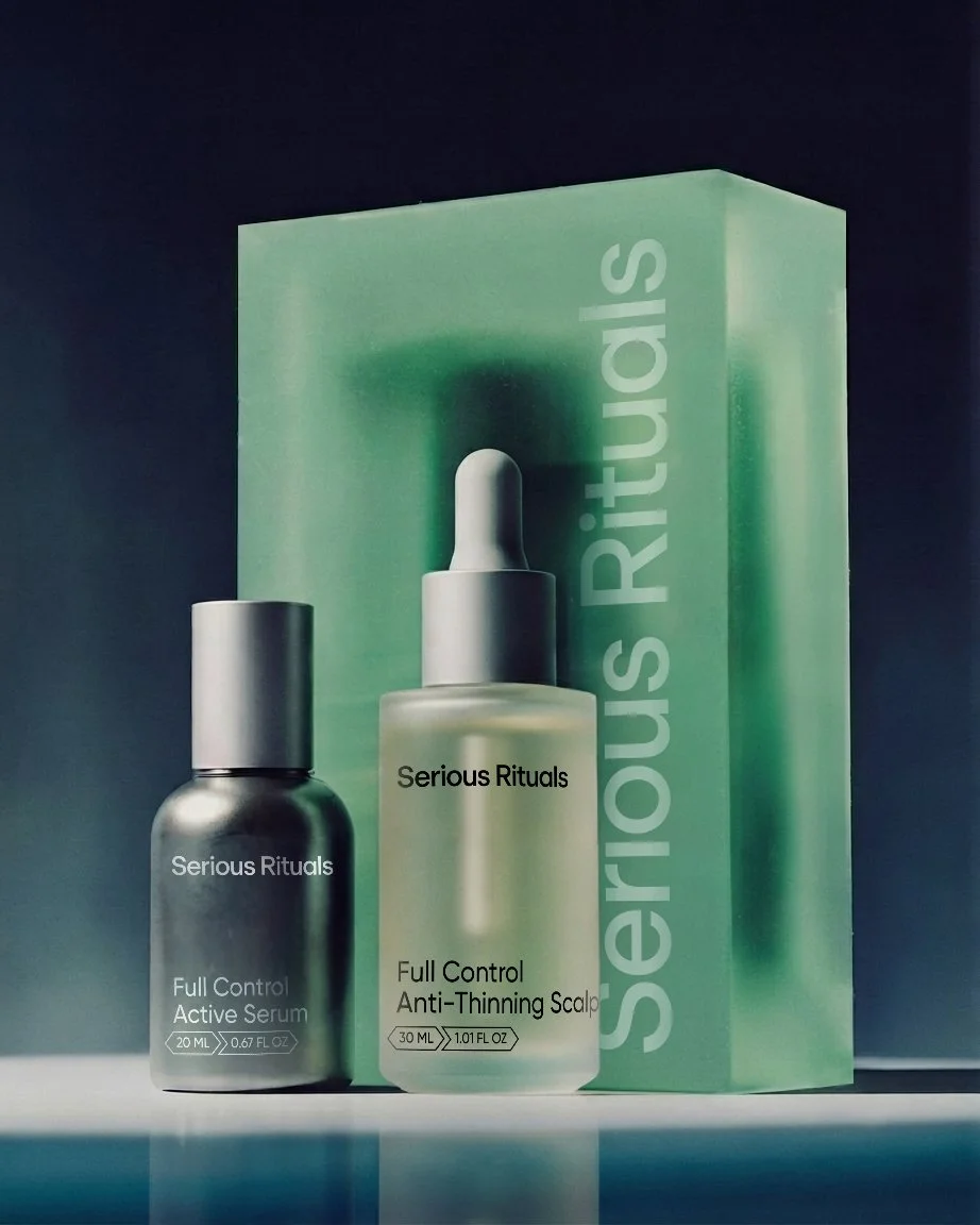 Serious Rituals skincare product set, including a bottle of Full Control Active Serum and a bottle of Full Control Anti-Thinning Scalp serum, with packaging behind them.