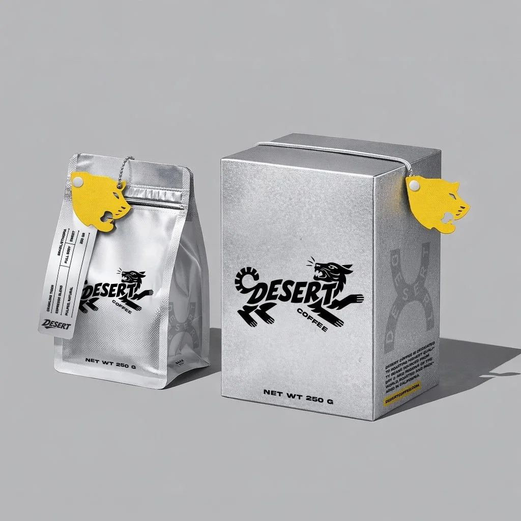 Silver coffee bag and box with Desert Coffee logo, yellow animal-shaped tags, on gray background.