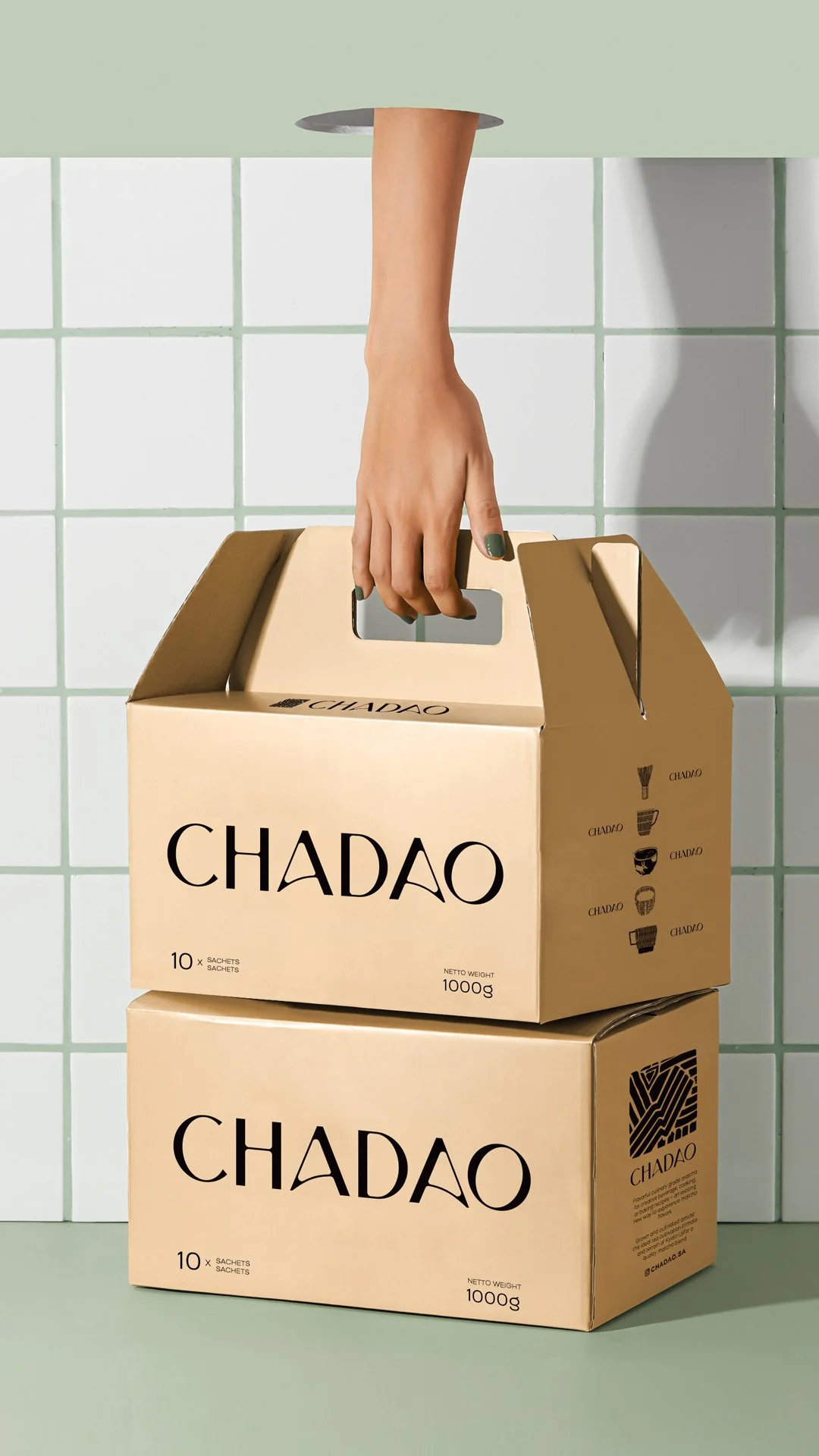 A hand reaching into a cardboard box labeled 'CHADAO' against a green tiled wall, with two more boxes labeled 'CHADAO' underneath.