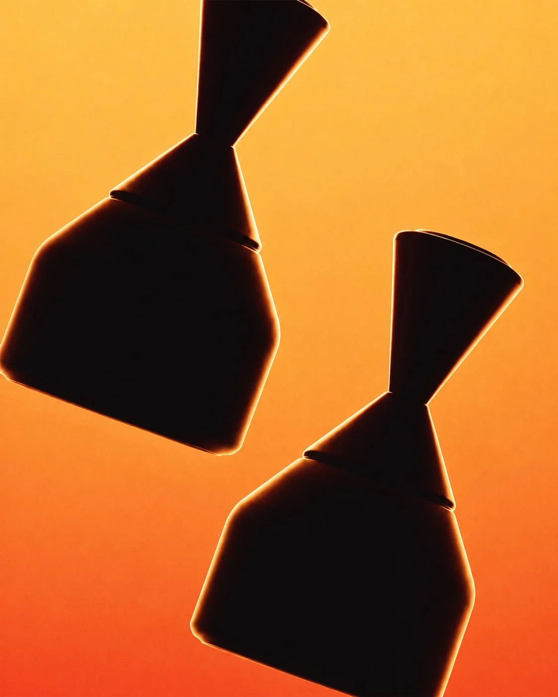 Silhouettes of sculptural luxury perfume bottles against orange light