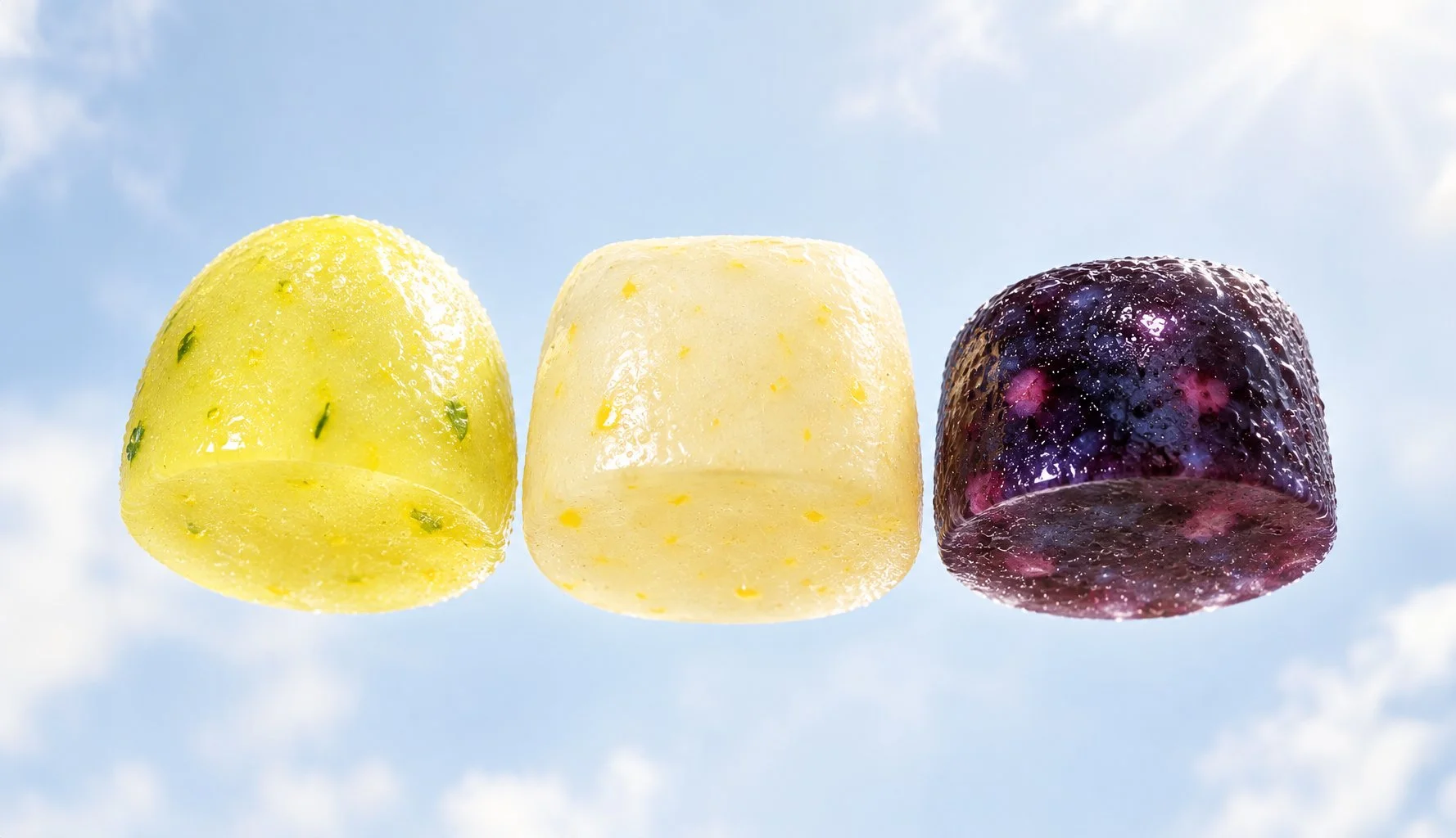 Three daily nutrition supplement gummies in yellow, white and purple