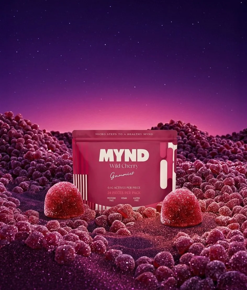 A bag of MYND Wild Cherry Gummies on a surface covered with cherries and cherry-shaped gummies, with a twilight sky background.