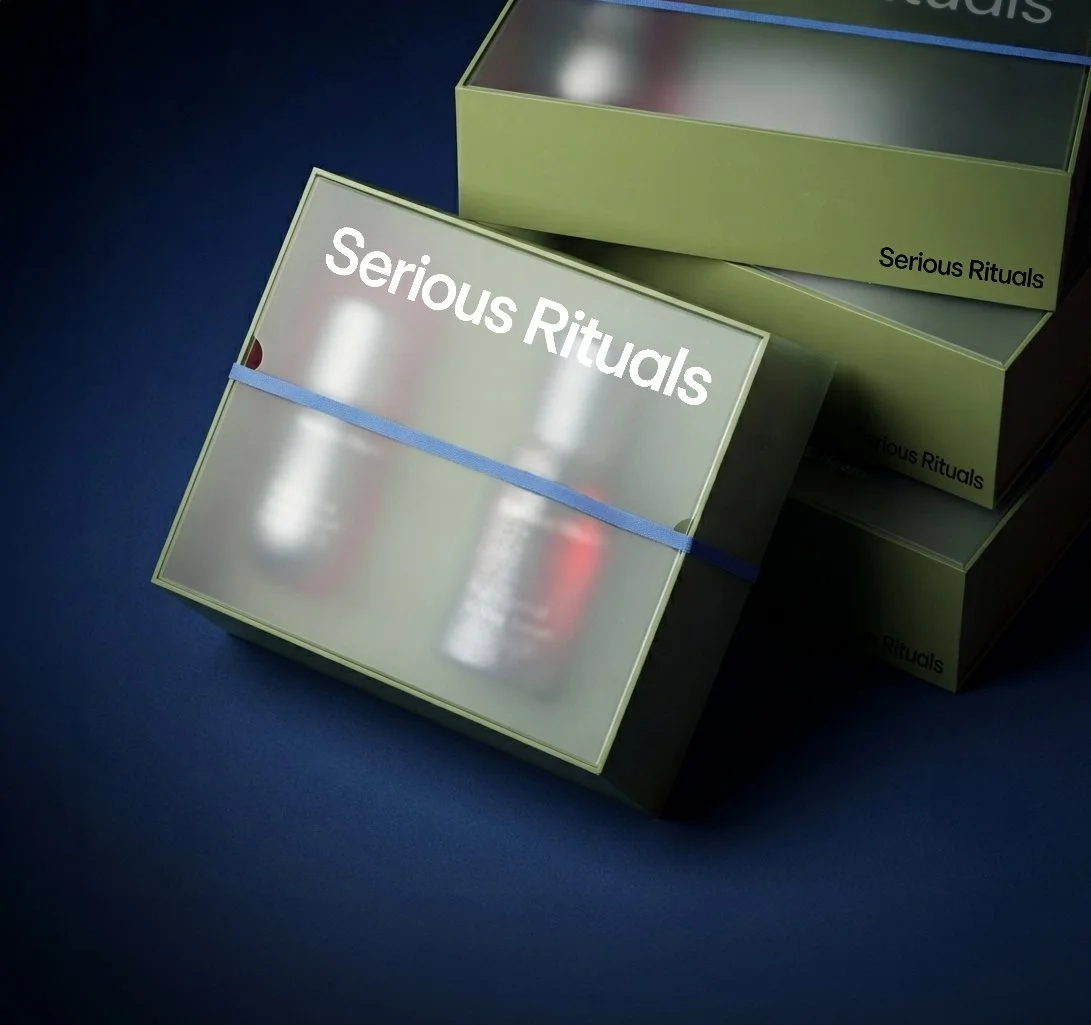 Boxes labeled 'Serious Rituals' stacked on a dark surface, with one box open revealing bottles inside.