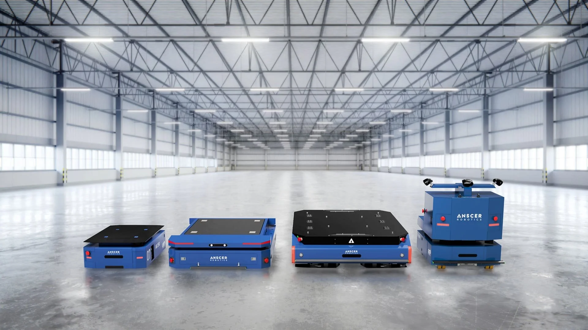 Four blue AGVs and AMRs are lined up next to each other in an empty beverage and food warehouse for automated material handling services, including tuggers and custom solutions.