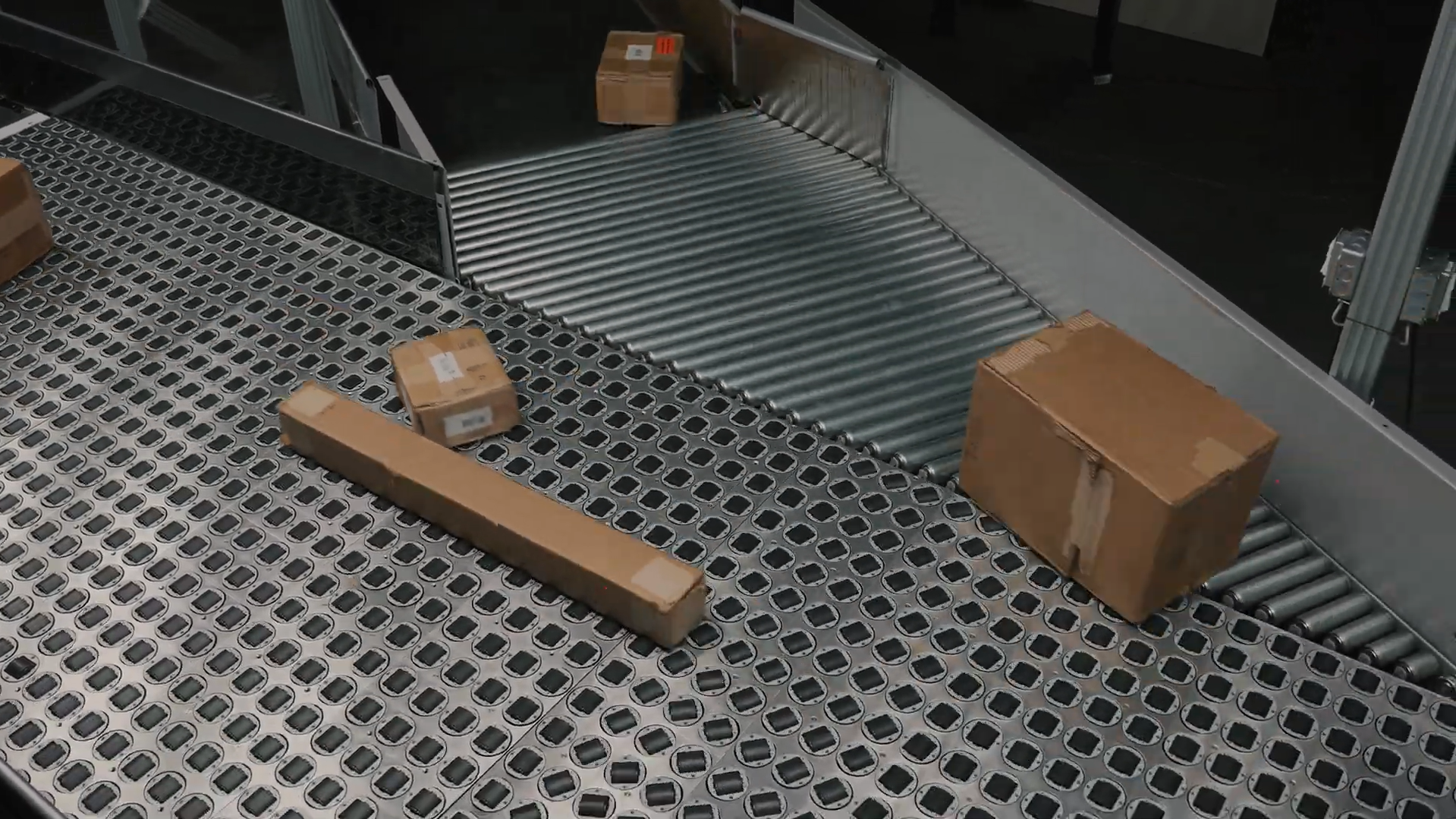 SmartSort steerable wheel sorter table with multiple wheels rotating to divert packages into MDR rollers for inbound and outbound automation.