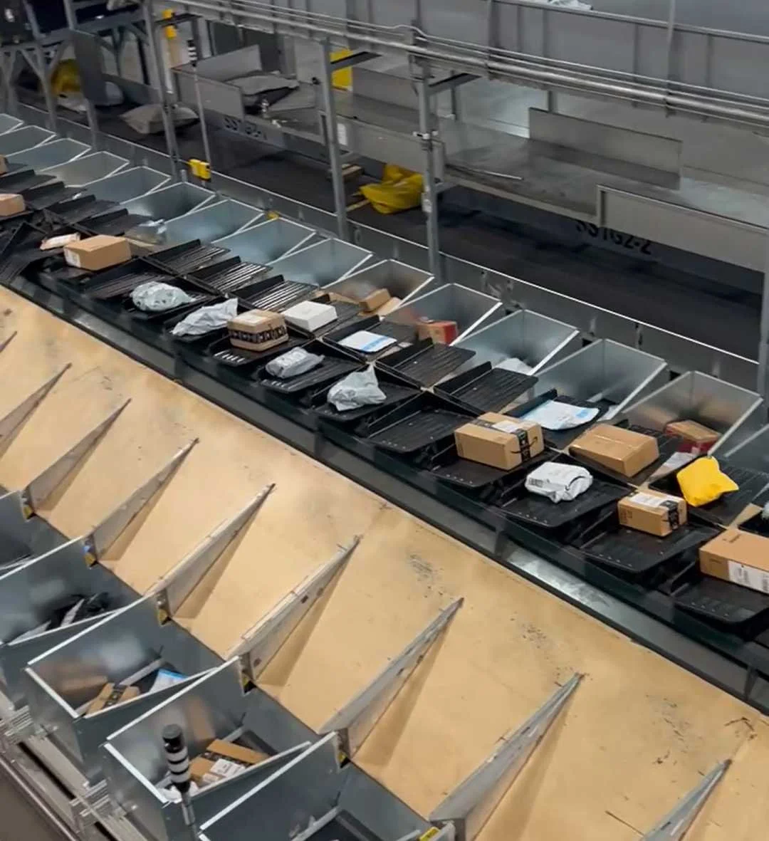 A tilt tray sorter sorting packages and products into containerized bins in a high-throughput distribution facility.