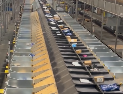 An Aegis Automated Smalls Bagging (ASB) system with a tilt tray sorter diverting packages into SmartBins in a distribution facility.