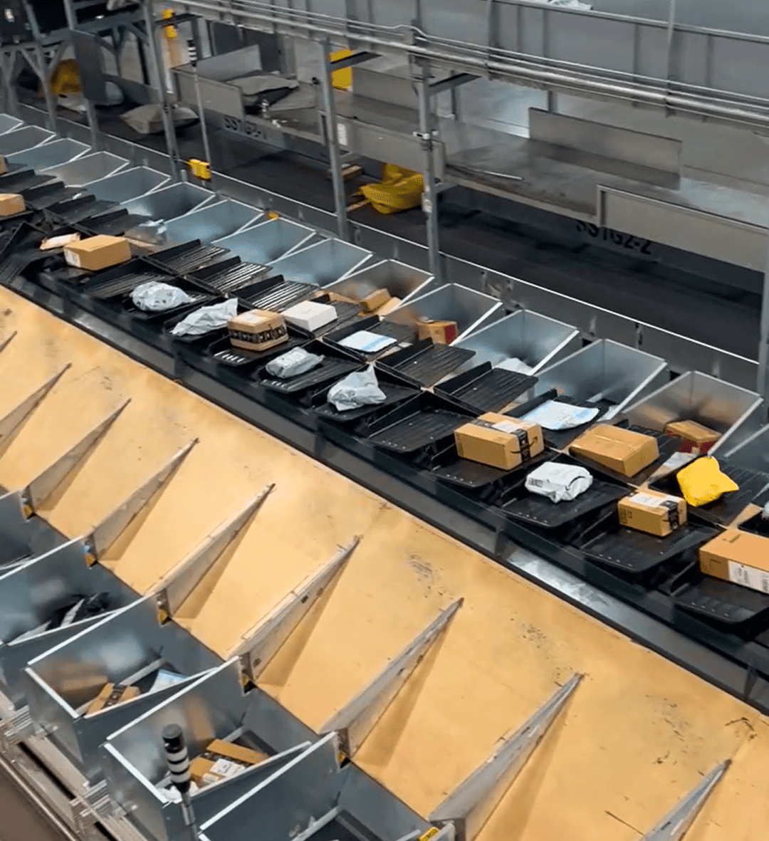 Automated Smalls Bagging (ASB) system with tilt tray sorter transporting parcels into smart bins for end-to-end automated sorting and distribution.