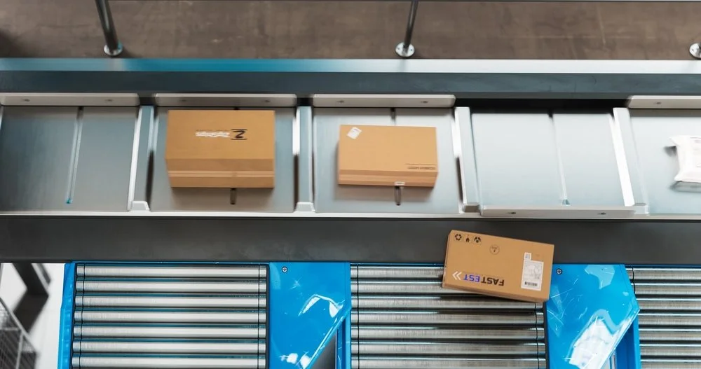 Packages on a warehouse conveyor moving right to left in an automated distribution center.