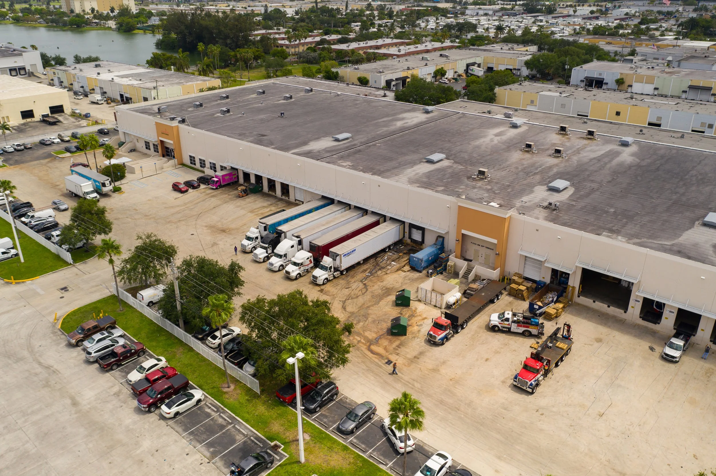 Exterior view of a food and grocery distribution center with semi trailers parked at loading docks and a parking lot.