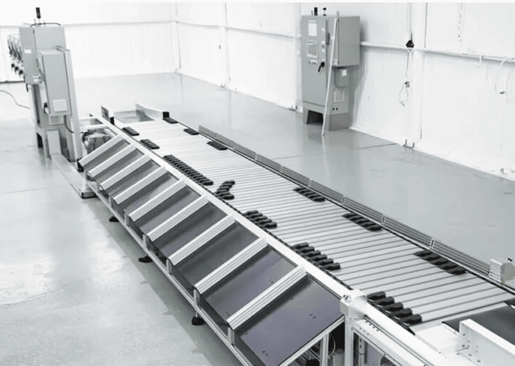 A sliding shoe sorter with black shoes moving left and right to divert packages in an empty warehouse distribution center environment.