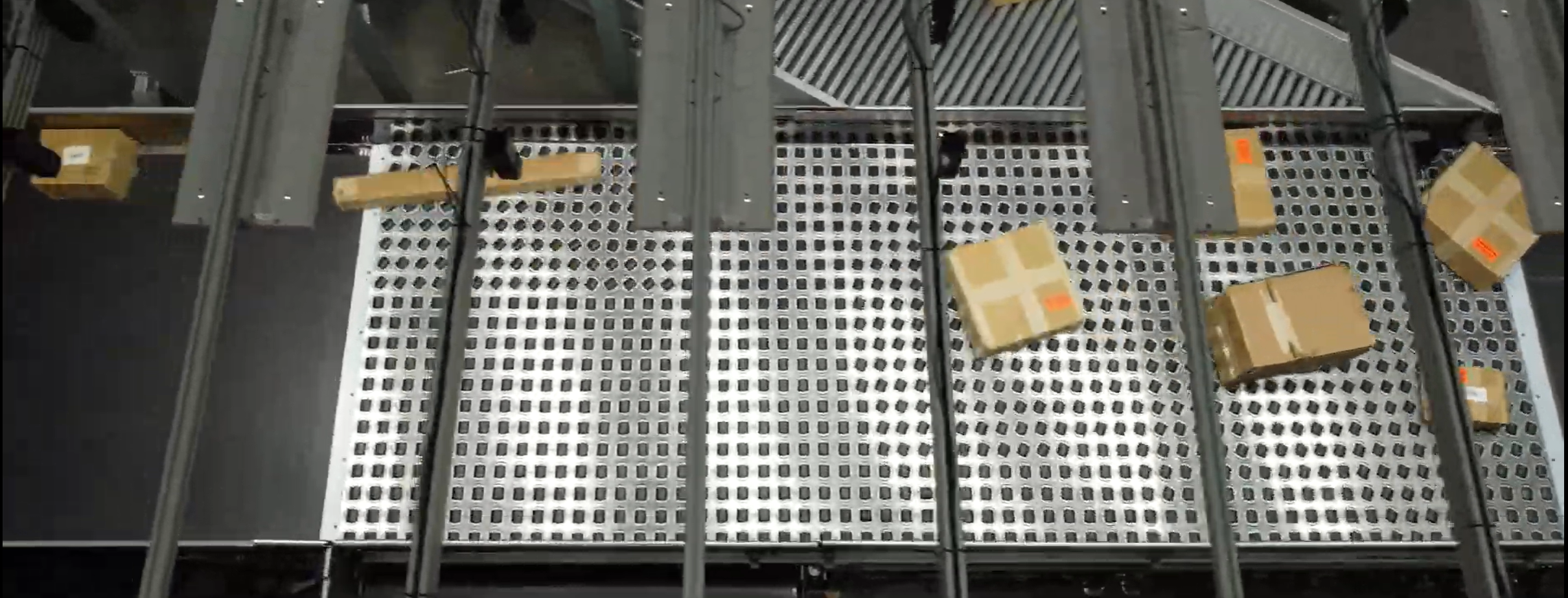 Aegis' TetraSort Singulator integrated into conveyor belt with black steerable swivel wheels lining up and gapping multiple boxes to the top of the conveyor.