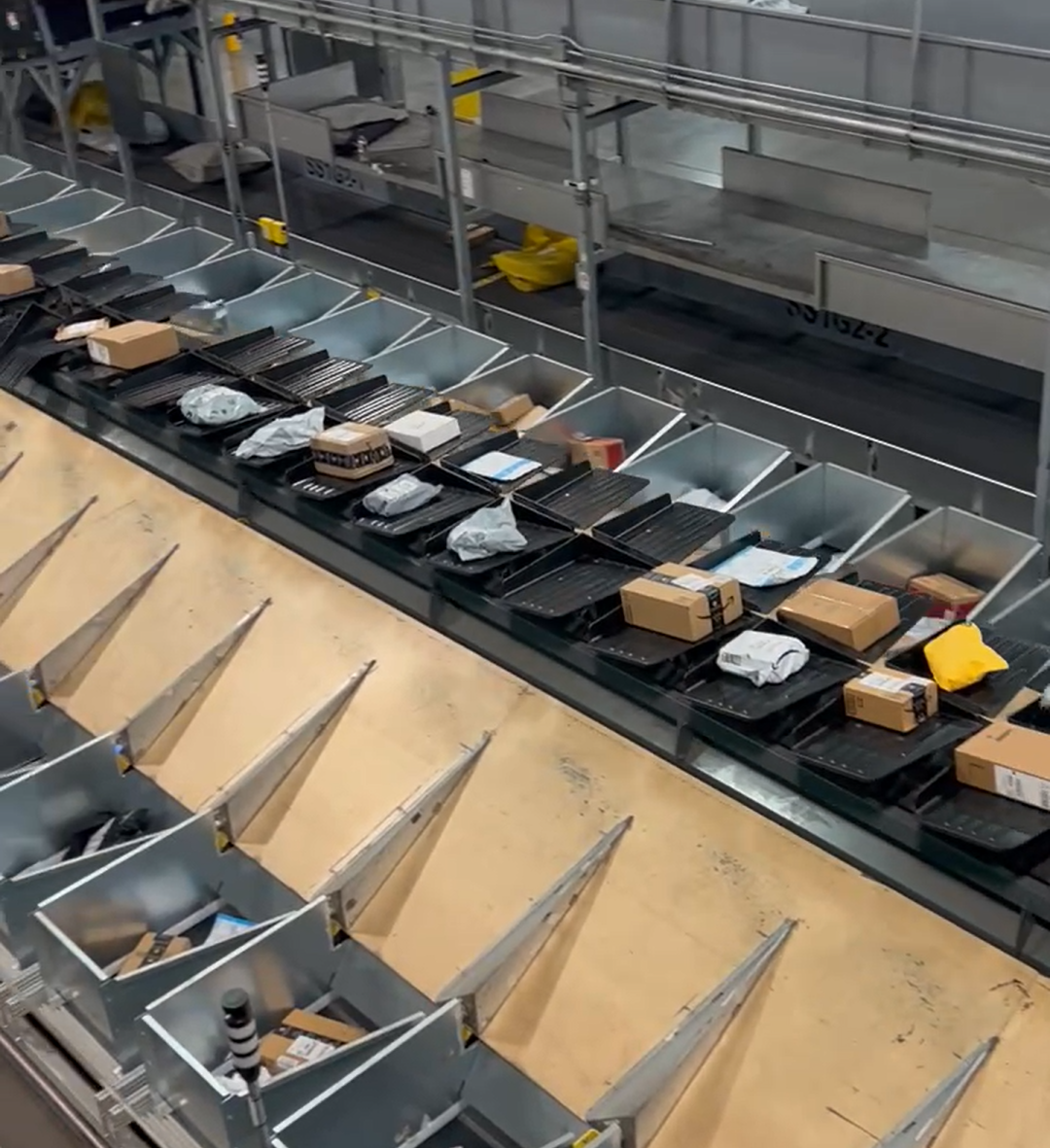 Aegis Automated Smalls Bagging (ASB) system showing parcels being moved on tilt tray sorter and dropped into SmartBins in parcel operation.