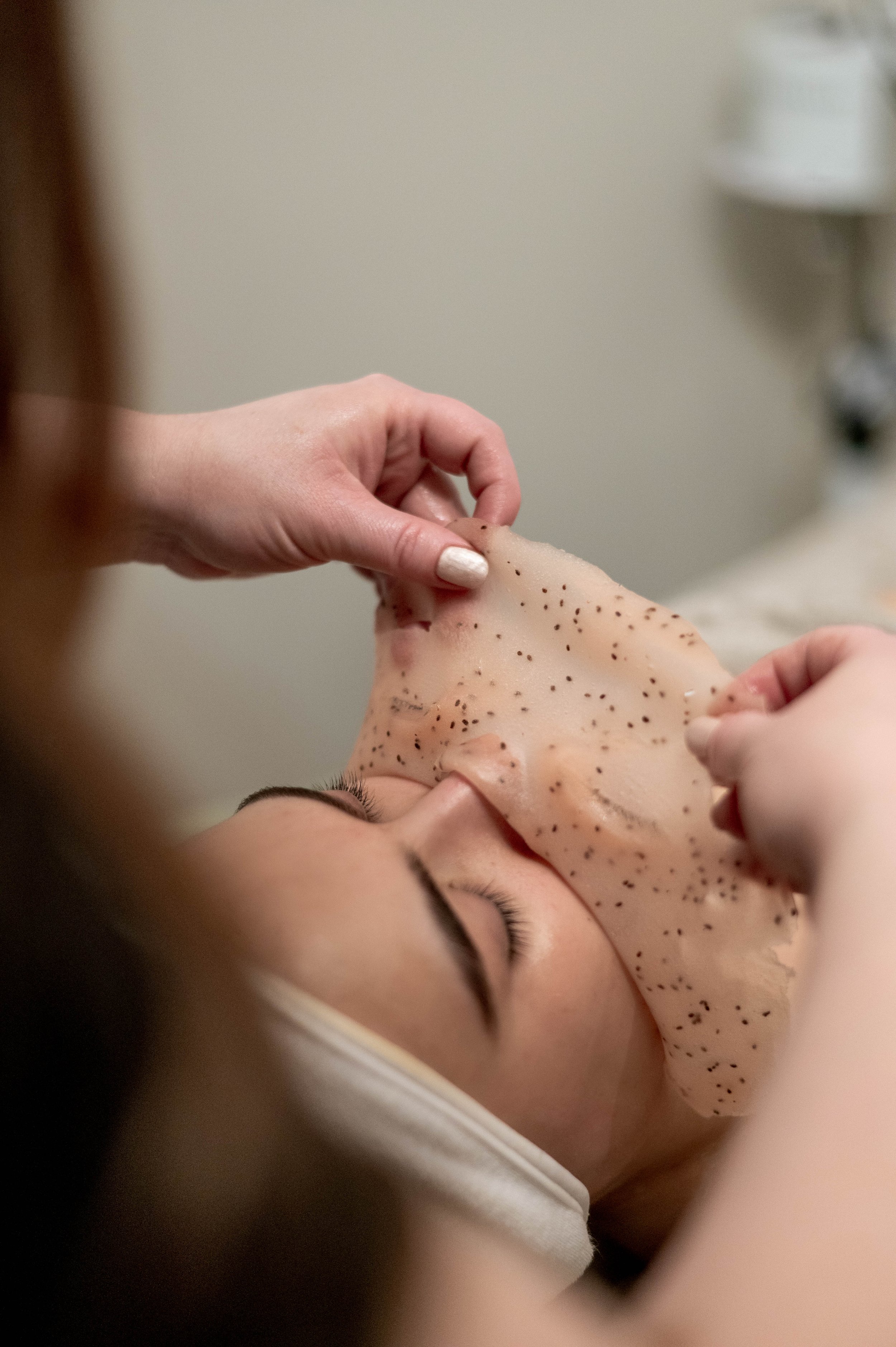 A person receiving a patch test on their forearm while lying down, with another person gently applying the patch to their skin.