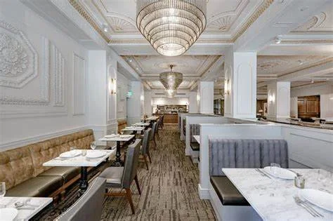 Elegant restaurant interior with white walls, chandeliers, and a mix of dining tables and booths