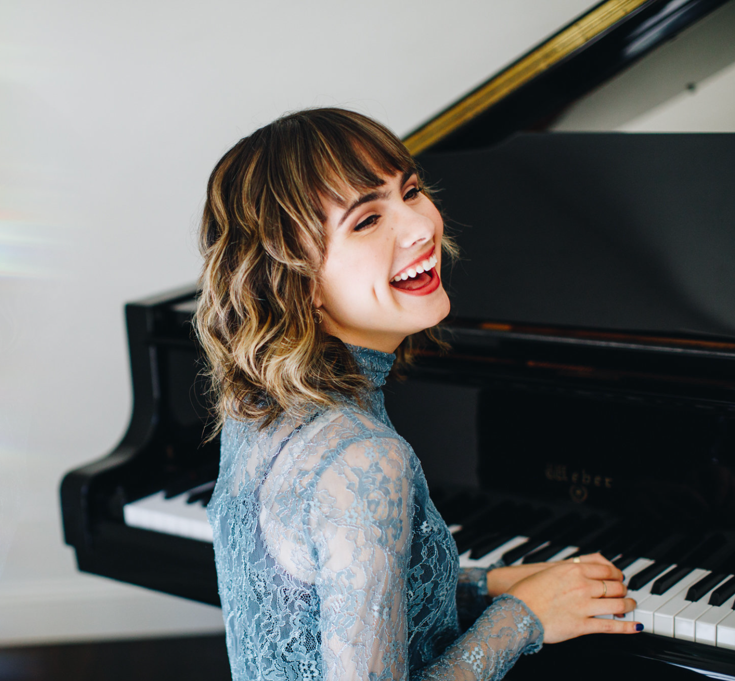 Woman smiling playing piano in a loft NYC