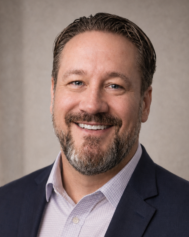 A man with a beard and short hair smiling, wearing a plaid blazer over a dark polo shirt, standing in front of a dark blue background with a logo that reads 'MJYC.tech'.