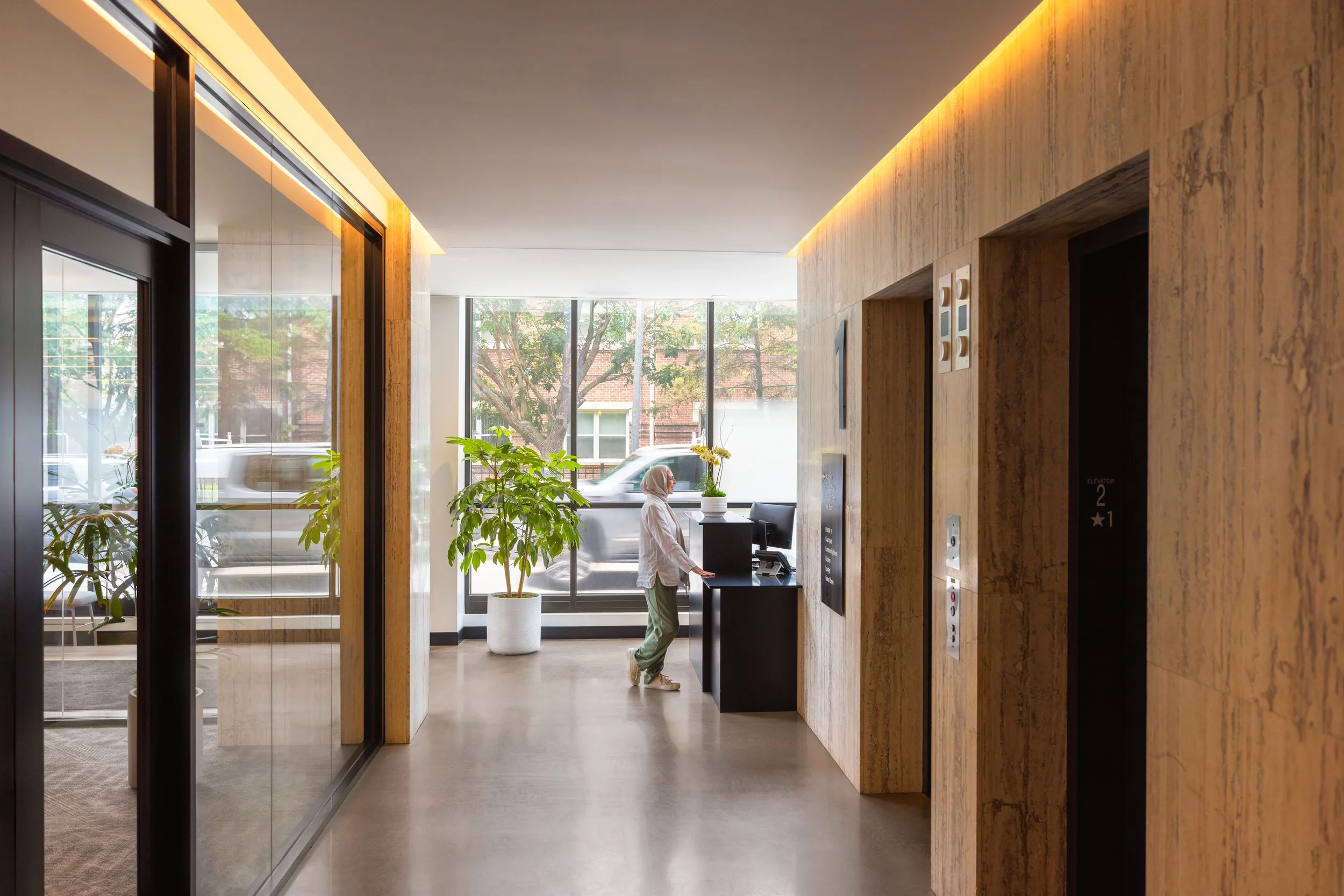 A woman in a hijab speaks to somebody at the front desk of the 440 Alfred lobby at City Modern.