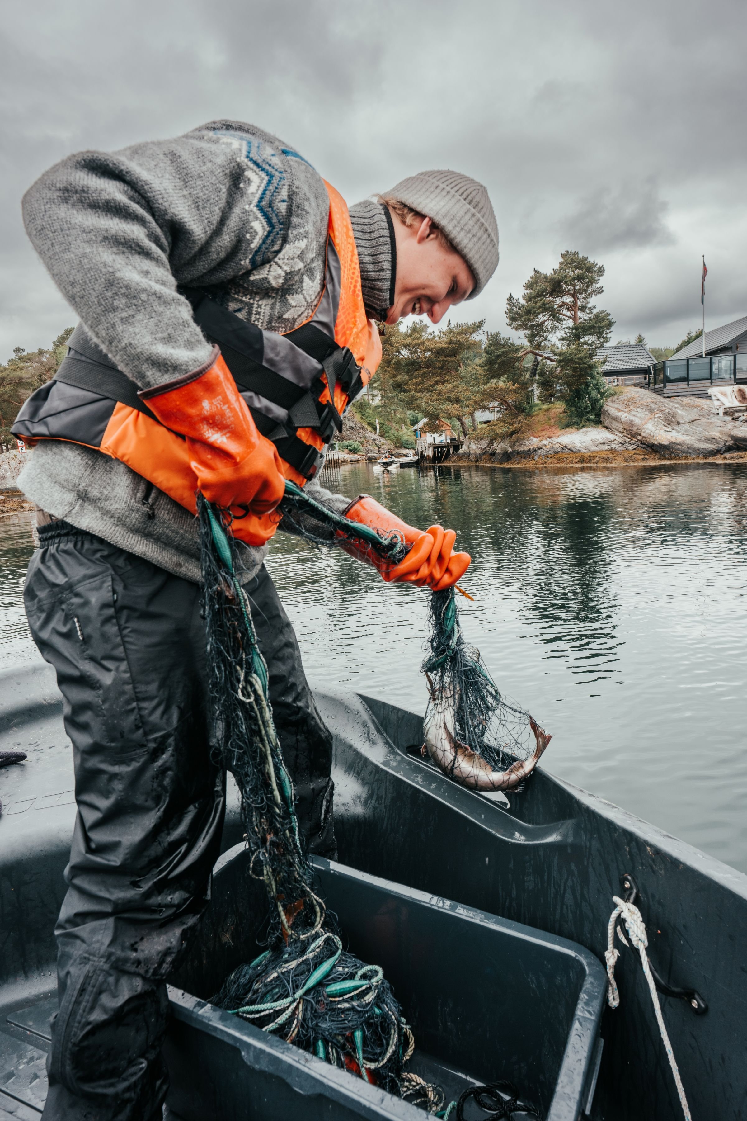 Person i båt som smiler av fisk i garn