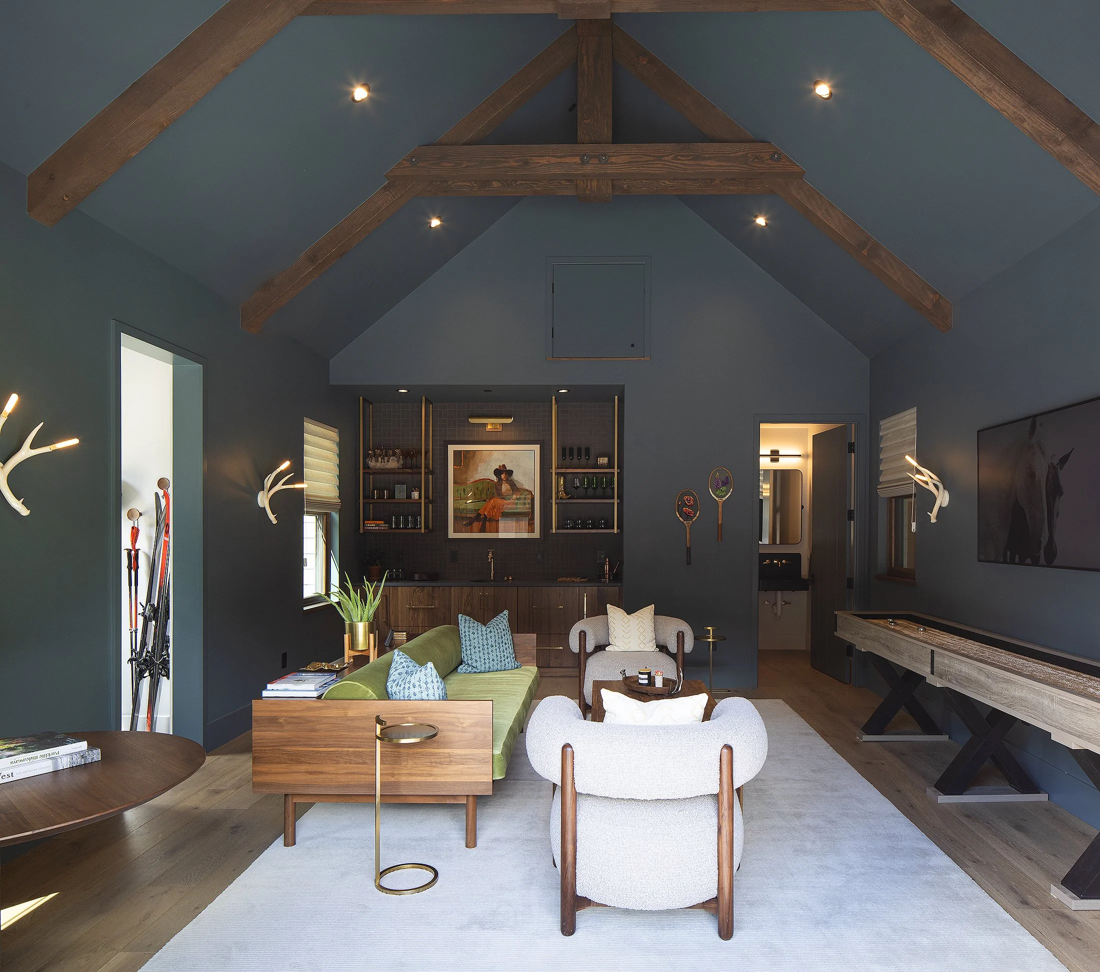 Game room with white chair in foreground wet bar in the foreground and shuffle ball table to the right green walls 