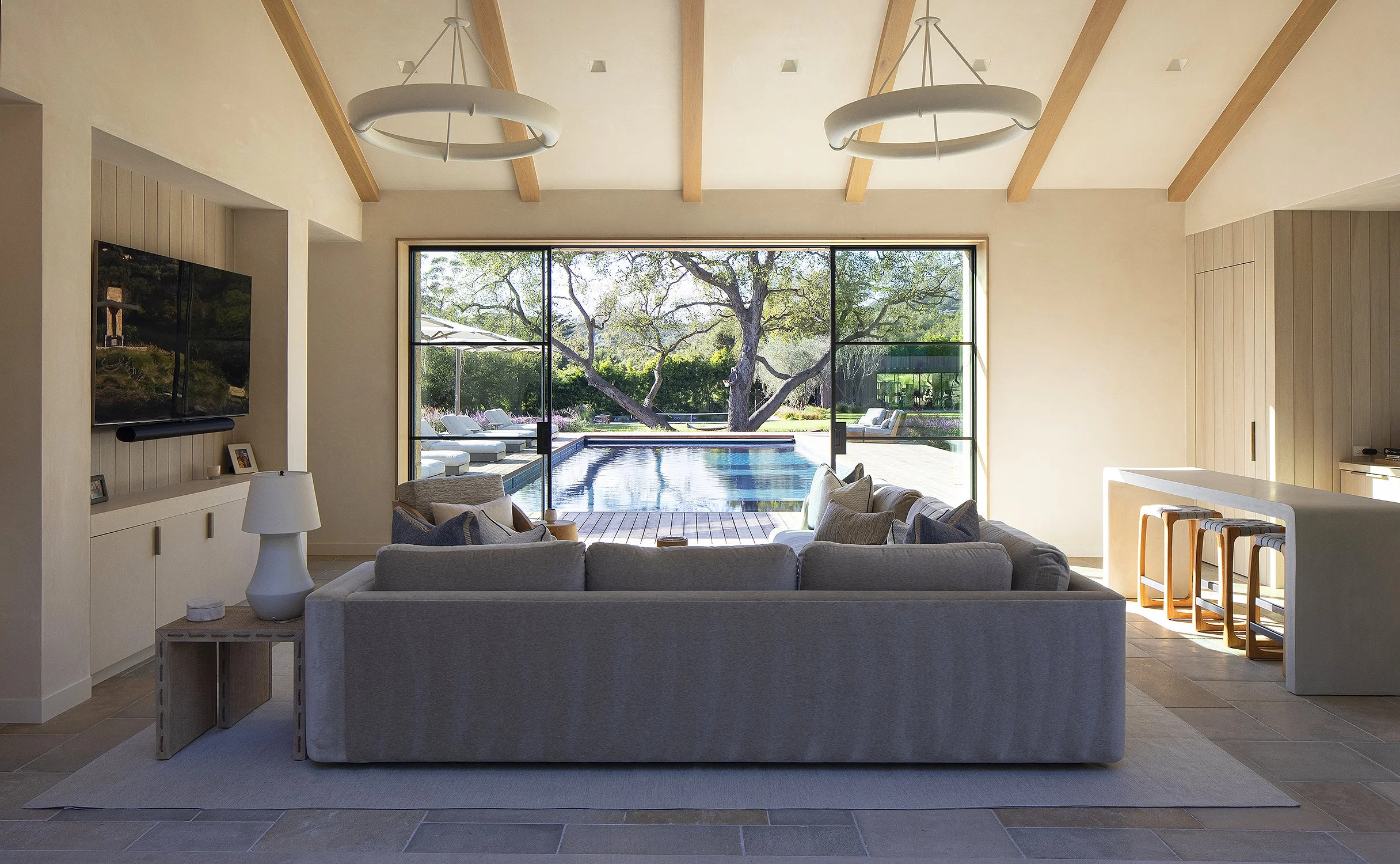 Pool room with pool in the background and blue couch in the foreground inn this incredible home in Montecito California 